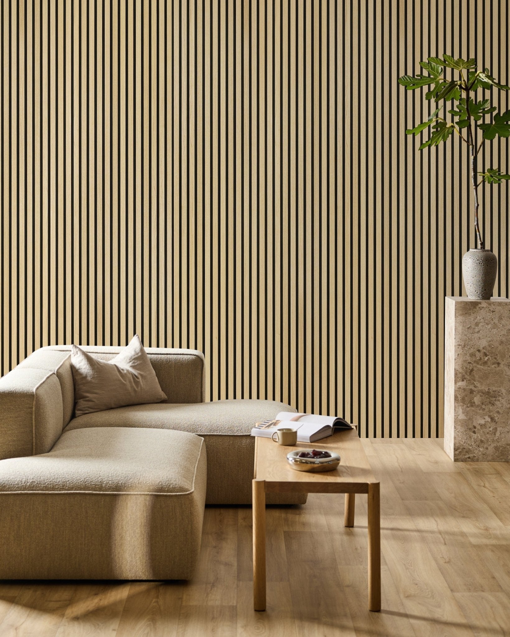 Living room with a Classic Oak Akupanel acoustic slat wall behind a beige sofa, wood table and tall plant.