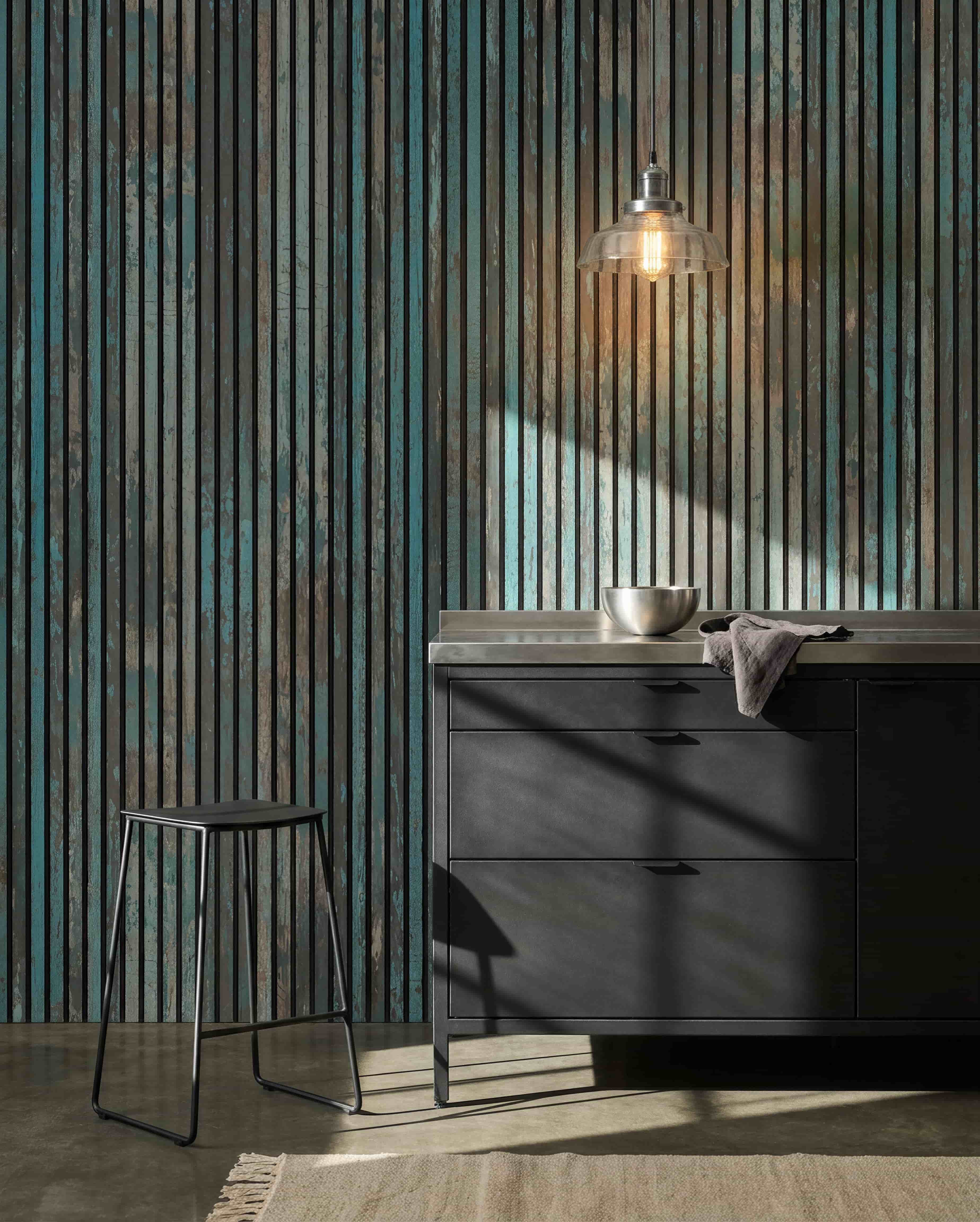 Modernt kök med black pallar, black skåp, en skål under en glödlampa och en WoodUpp Akupanel Oxide Blue Akustikpanel på väggen för bättre ljudkomfort.