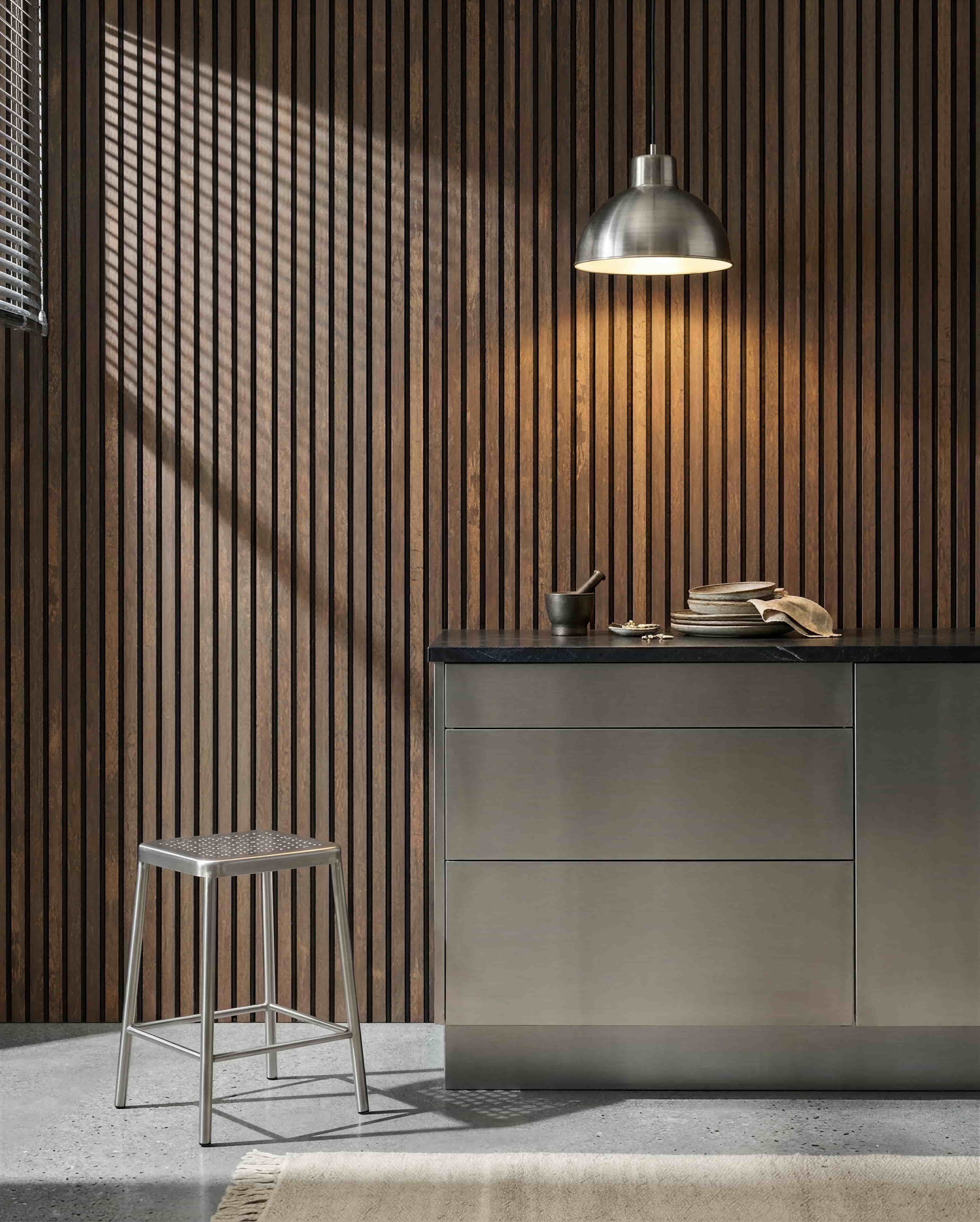 Kök med en WoodUpp Akupanel Oxide Copper akustisk ribbvägg, bänkskiva i rostfritt stål, metallpall, pendellampa, blandat porslin och mortel med stöt.