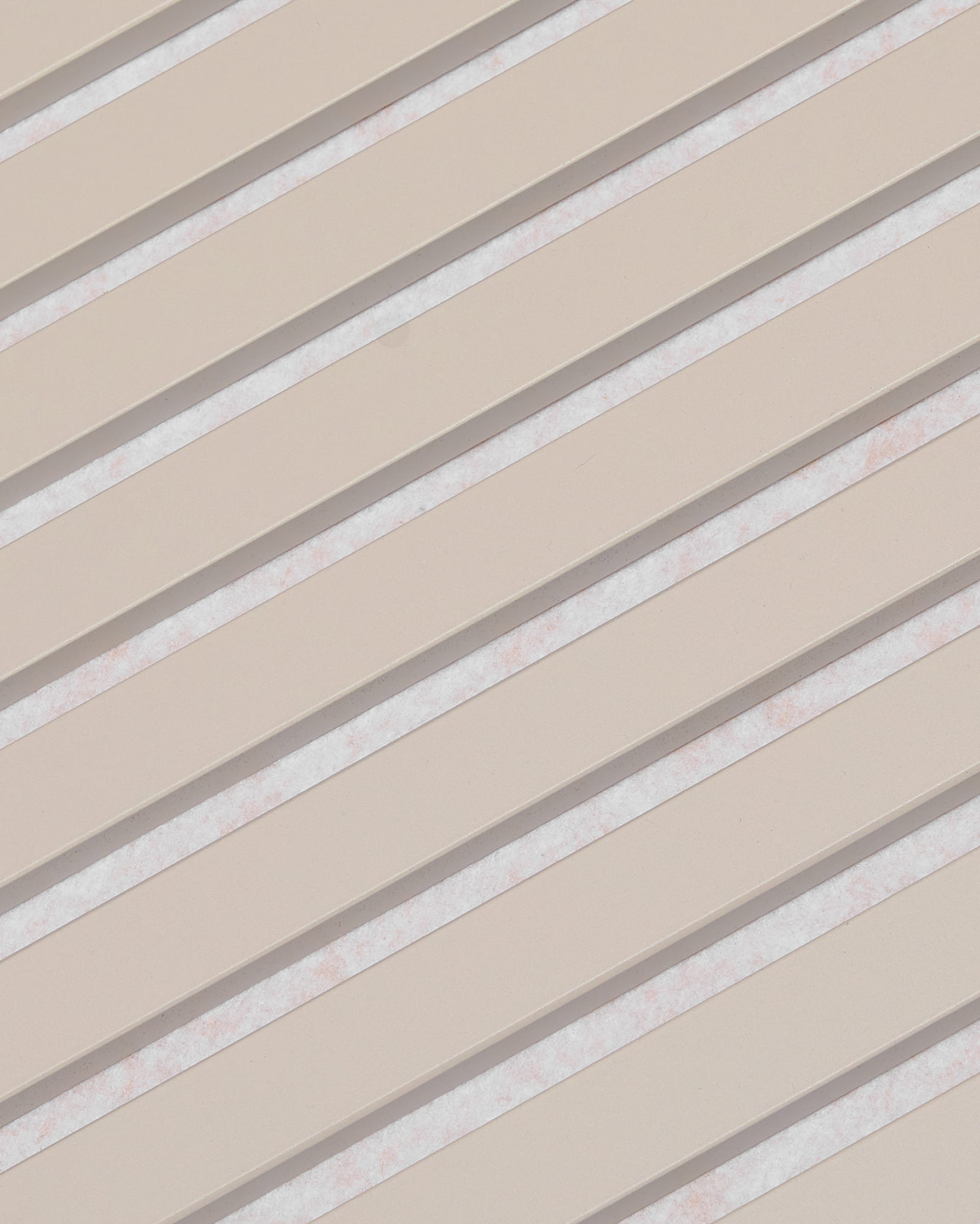 Diagonala beige lameller med vita mellanrum bildar ett randigt mönster på akustikpanelen WoodUpp Akupanel, med ytbehandlingen Soft Linen Light Beige Felt, 240 x 60 cm.