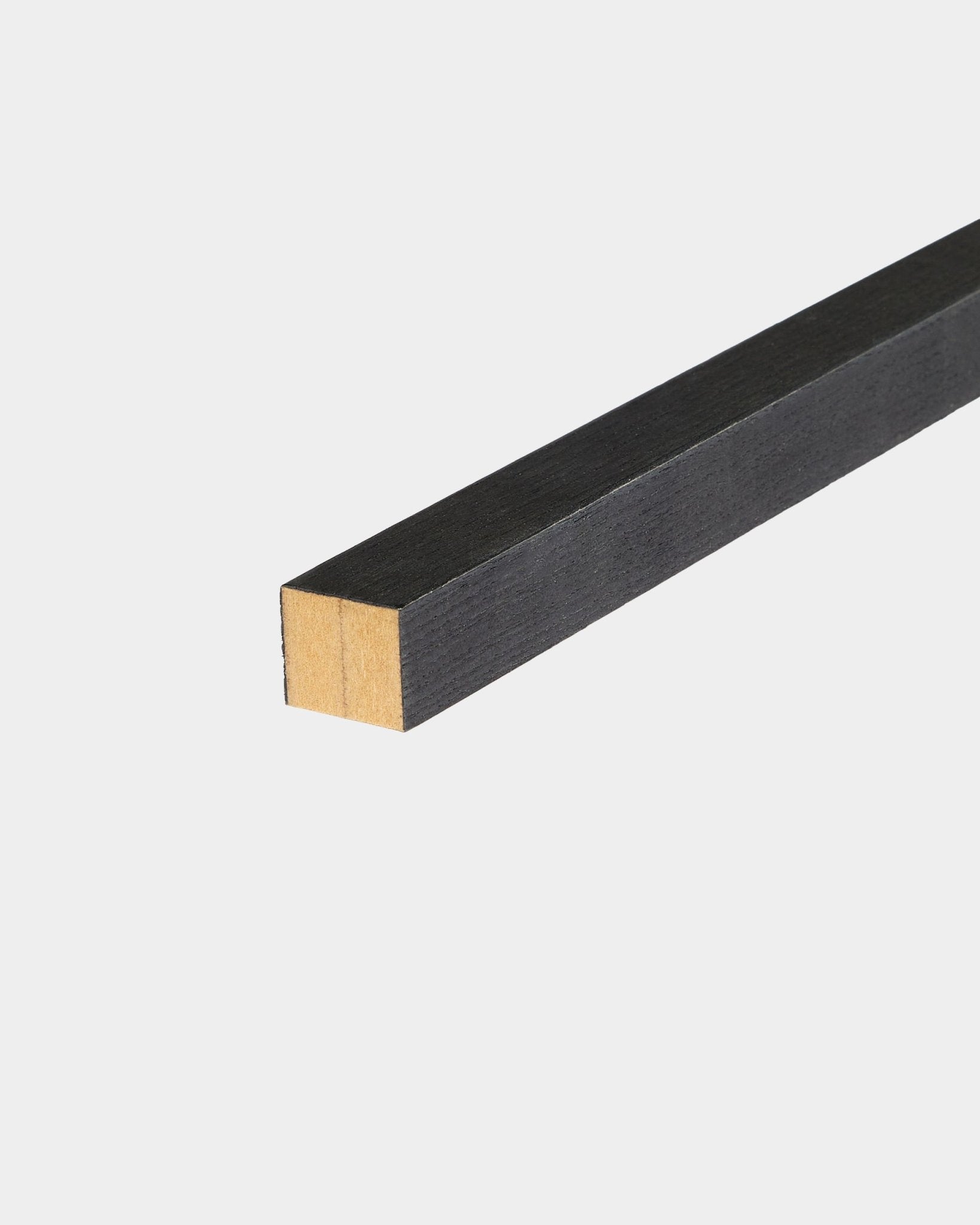 WoodUpp Black ändlamell i ask, 2,2 cm, utformad för Akupanel Akustikpanel-installation, placerad på en vit yta med ena änden obehandlad.