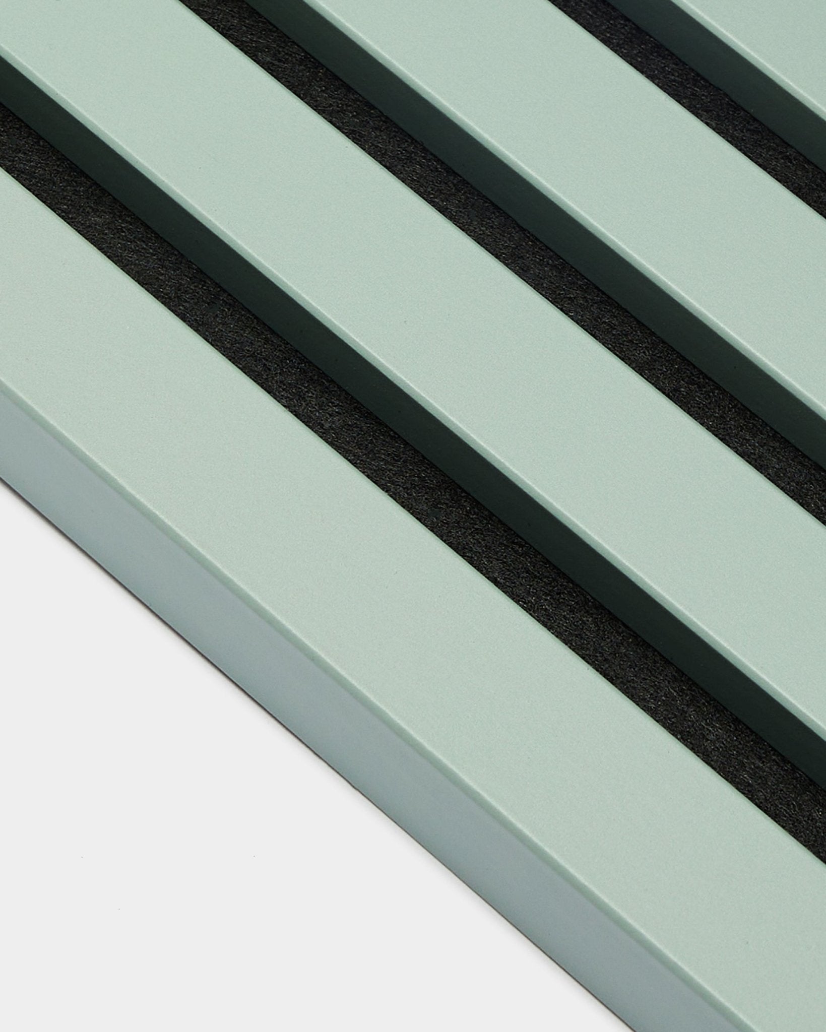 Närbild av tre parallella pastellgröna End Lamella / Cloud-lameller, 2,2 cm breda, från WoodUpp, som en del av en Akupanel Akustikpanel mot en ljus bakgrund.