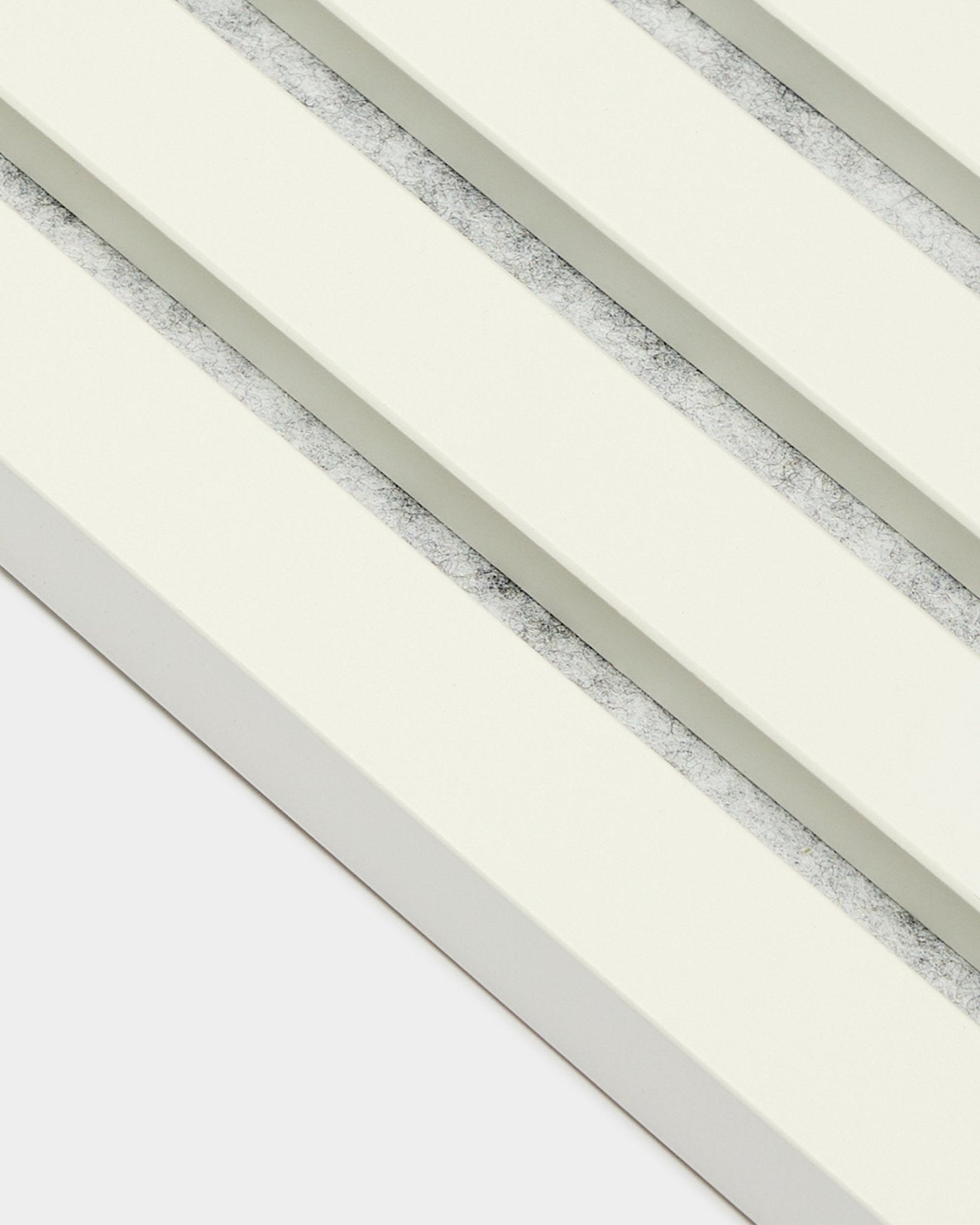 Fyra WoodUpp Akupanel ändlamell-/Snow akustikpaneler (2,2 cm) arrangerade diagonalt, med benvita ribbor och texturerade grå mellanrum i nordisk stil.