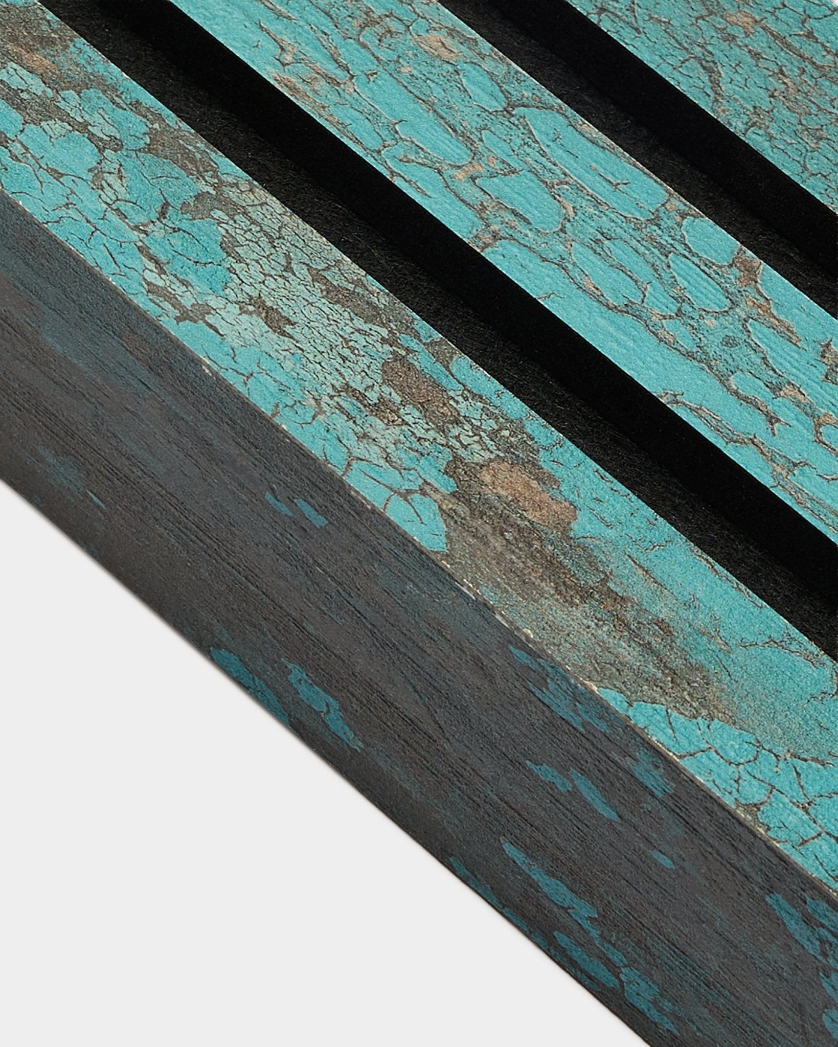Närbild av WoodUpp Akupanel ändlamell i Oxide Blue, 6,7 cm bred, med krackelerad blå färg och black spår på en rustik yta av Akustikpanel.