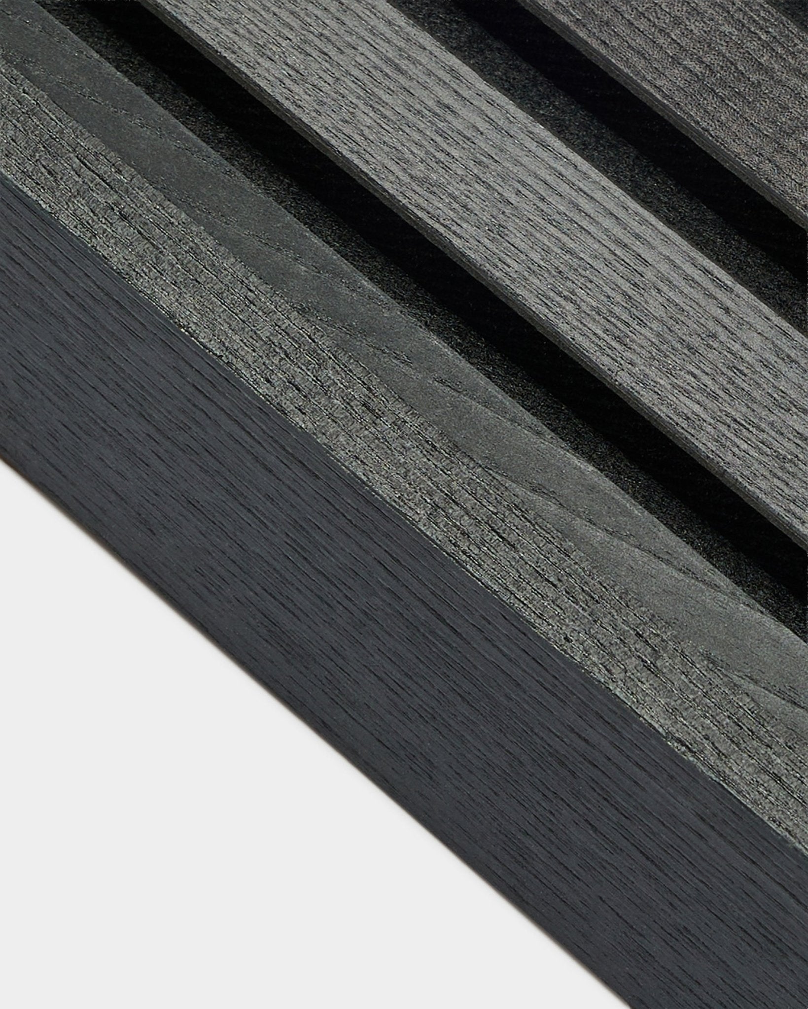 Närbild av WoodUpp Akupanel ändlamell i Black ask (6,7 cm), som visar mörkgrå träådring mot en ljus bas, utformad för nordiska Akustikpanel installationer.