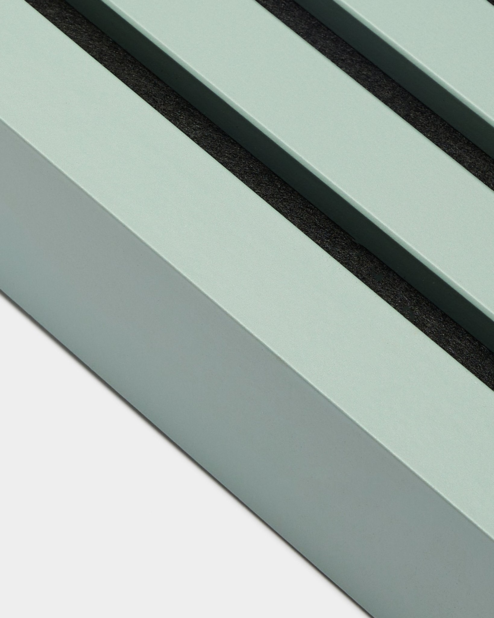 Närbild av WoodUpp installationsaccessoar för Akupanel: ändlamell i Cloud, 6,7 cm bred, mintgrön MDF-ram med två black-spår mot vit bakgrund.
