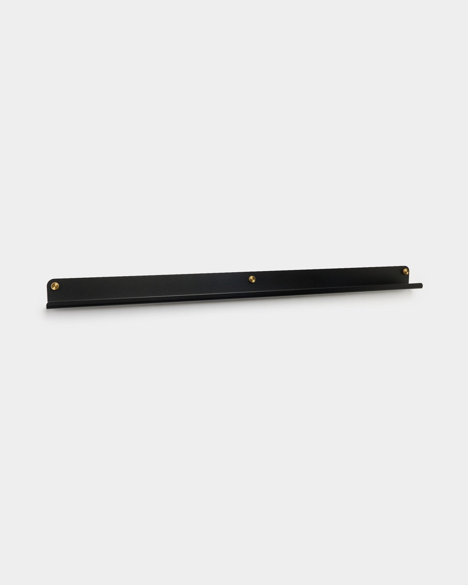 Den Norr smala hyllan i black från WoodUpp, 115,9 cm, väggmonterad med tre brass tumskruvar, visad mot en enkel vit bakgrund.