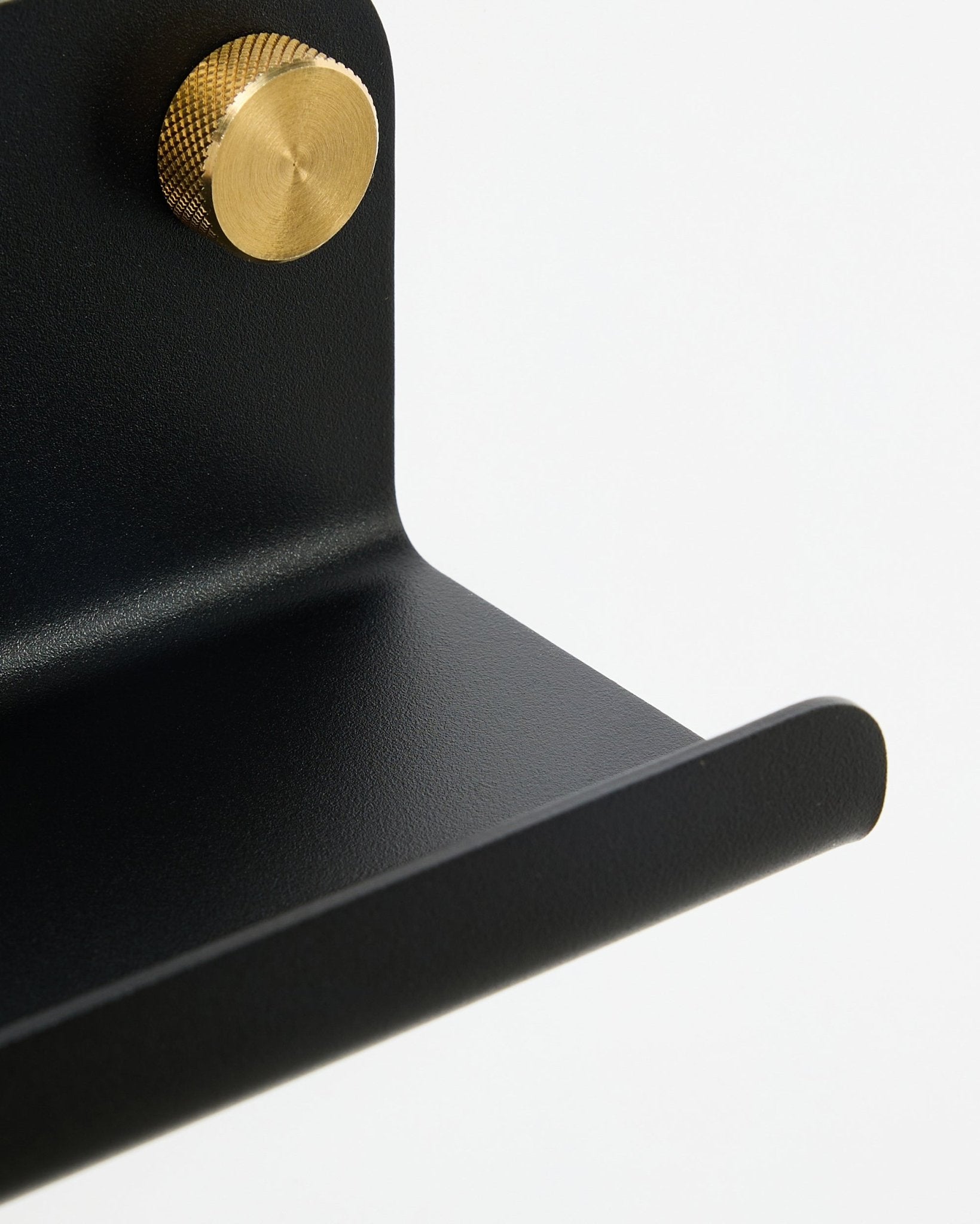 Närbild av WoodUpp Norr smal hylla i black, 75,9 cm, med en guldfärgad knoppr med struktur, visad mot en vit bakgrund.