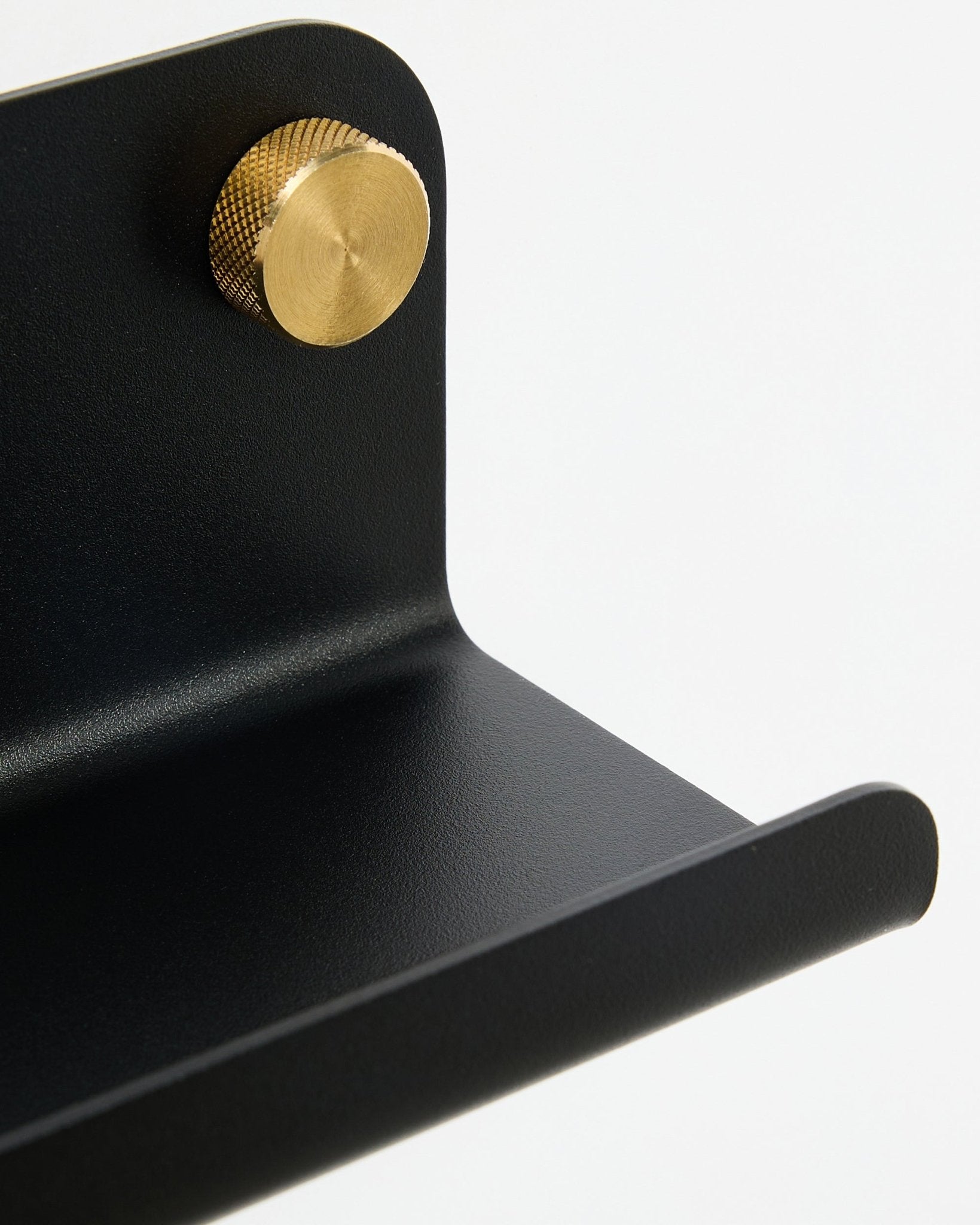 Närbild av WoodUpp Norr smal hylla, 35,9 cm, black steel med rundad kant och guldfärgad knopp, visad mot en vit bakgrund.