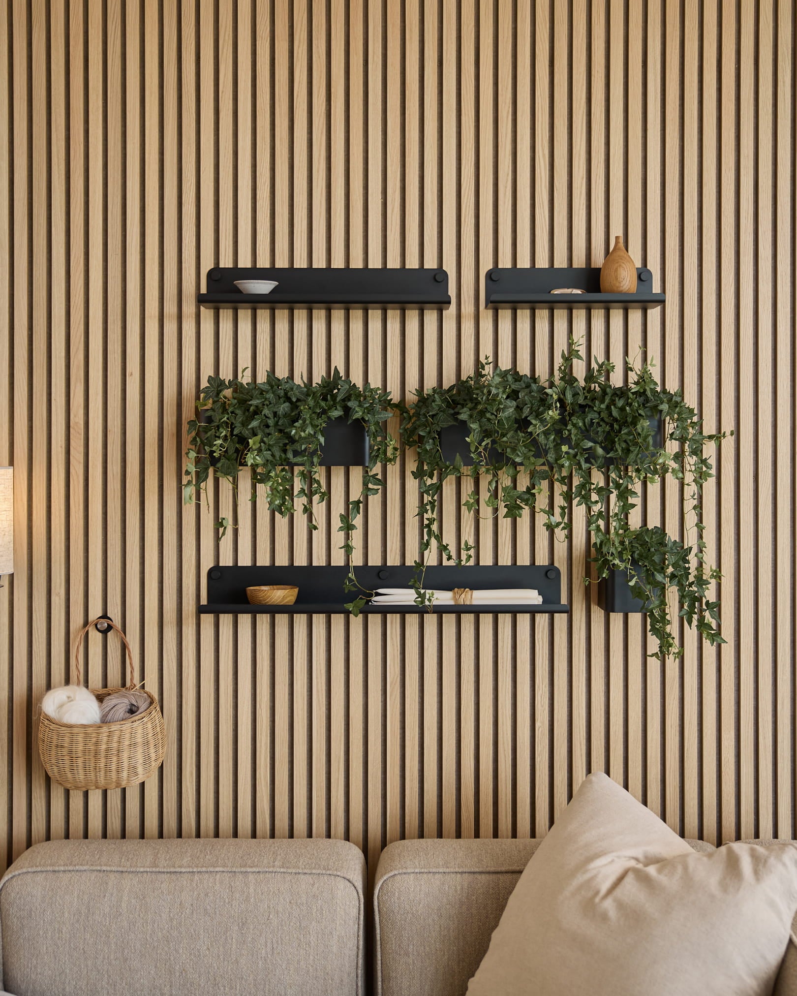 Modernt vardagsrum med en nordisk akustisk ribbpanel, black hyllor, hängande växter i WoodUpps Norr Plant Box (35,9 cm, Black) och en beige soffa.