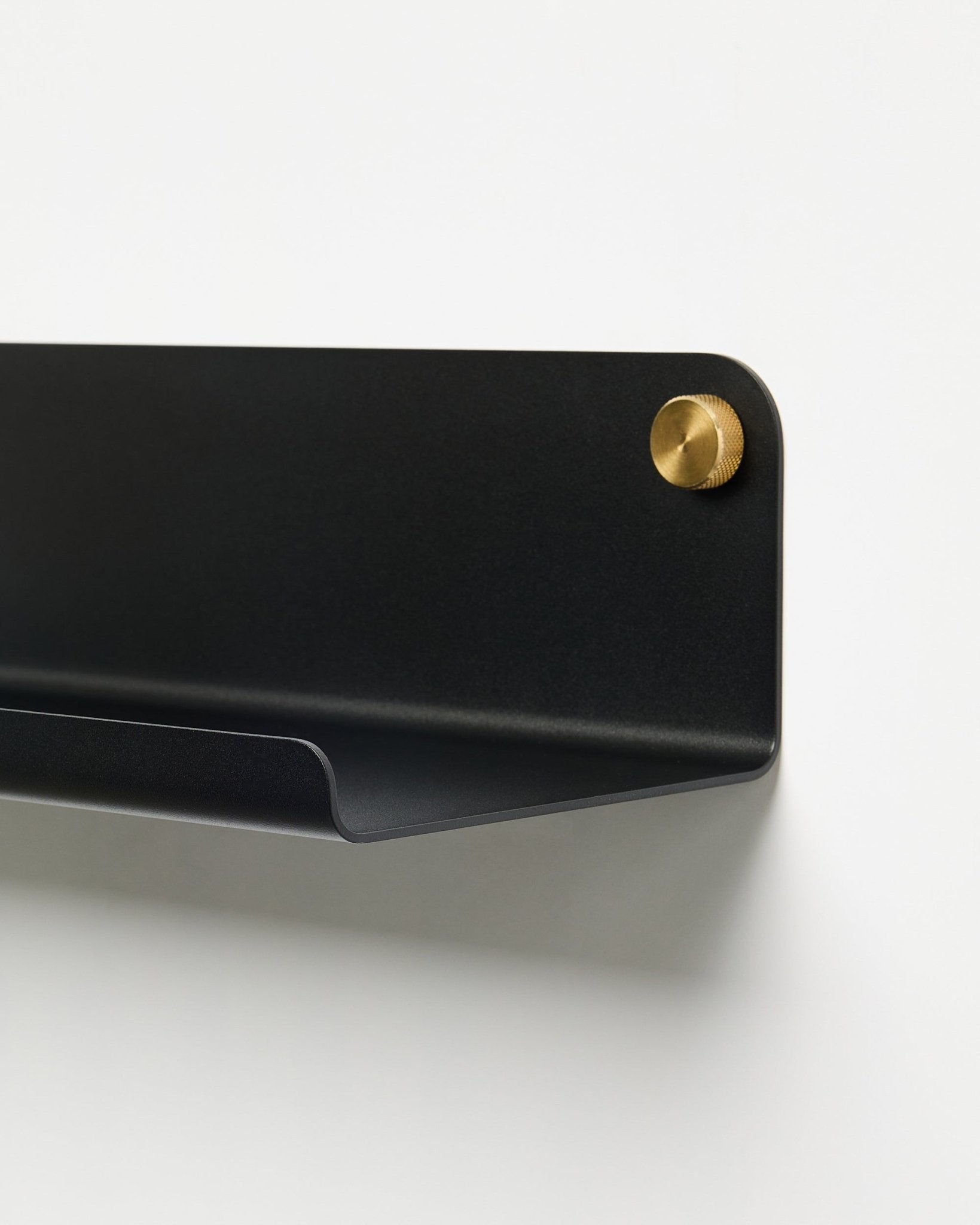 Närbild på tillbehöret WoodUpp Norr Wide Shelf (51,9 cm) i pulverlackerad black metall med guldfärgad skruv, placerad mot en enkel vit bakgrund.