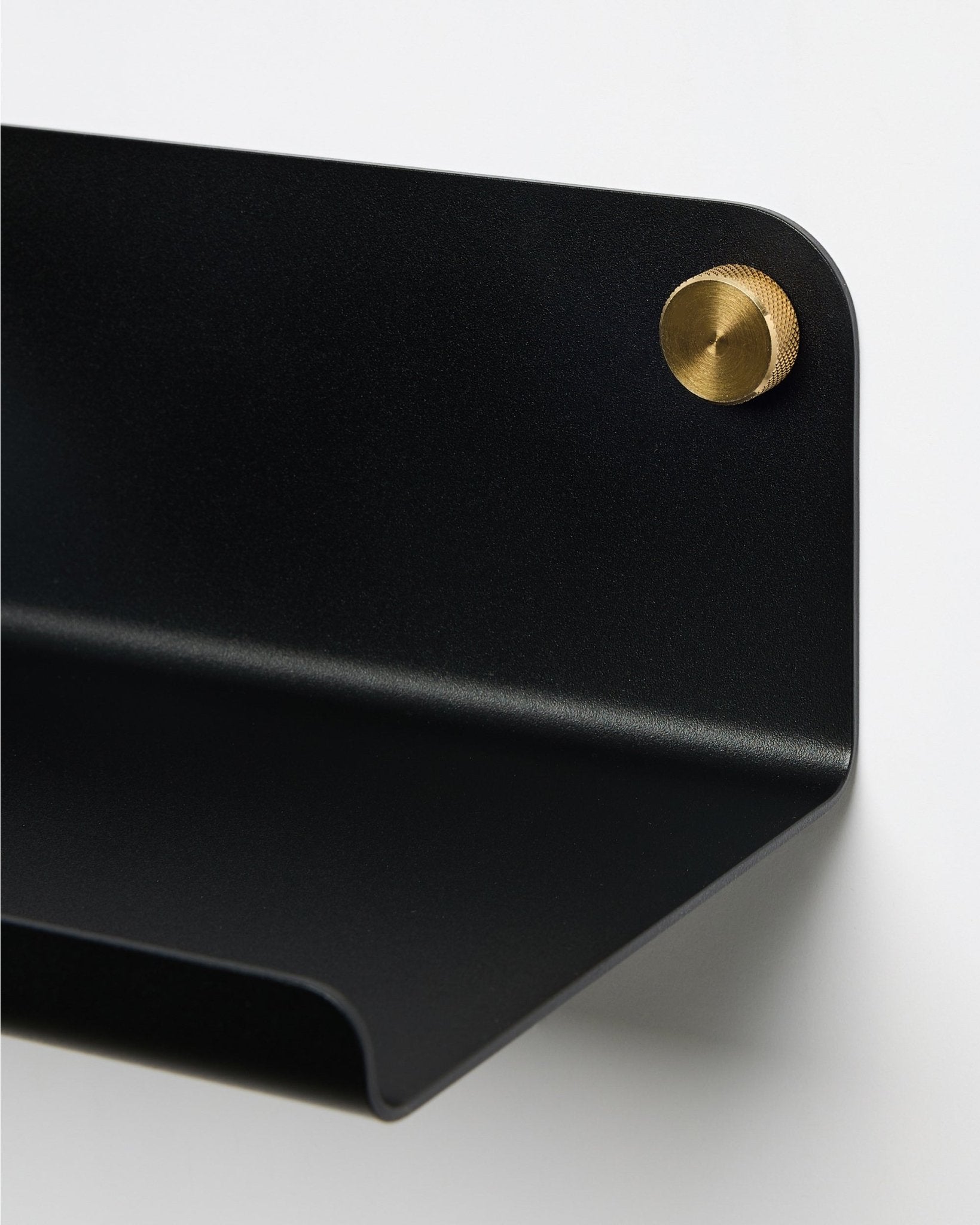 Närbild av WoodUpp Norr bred hylla i black, 35,9 cm, med rundad kant, fäst på väggen med en rund brass skruv. Nordisk minimalistisk design.