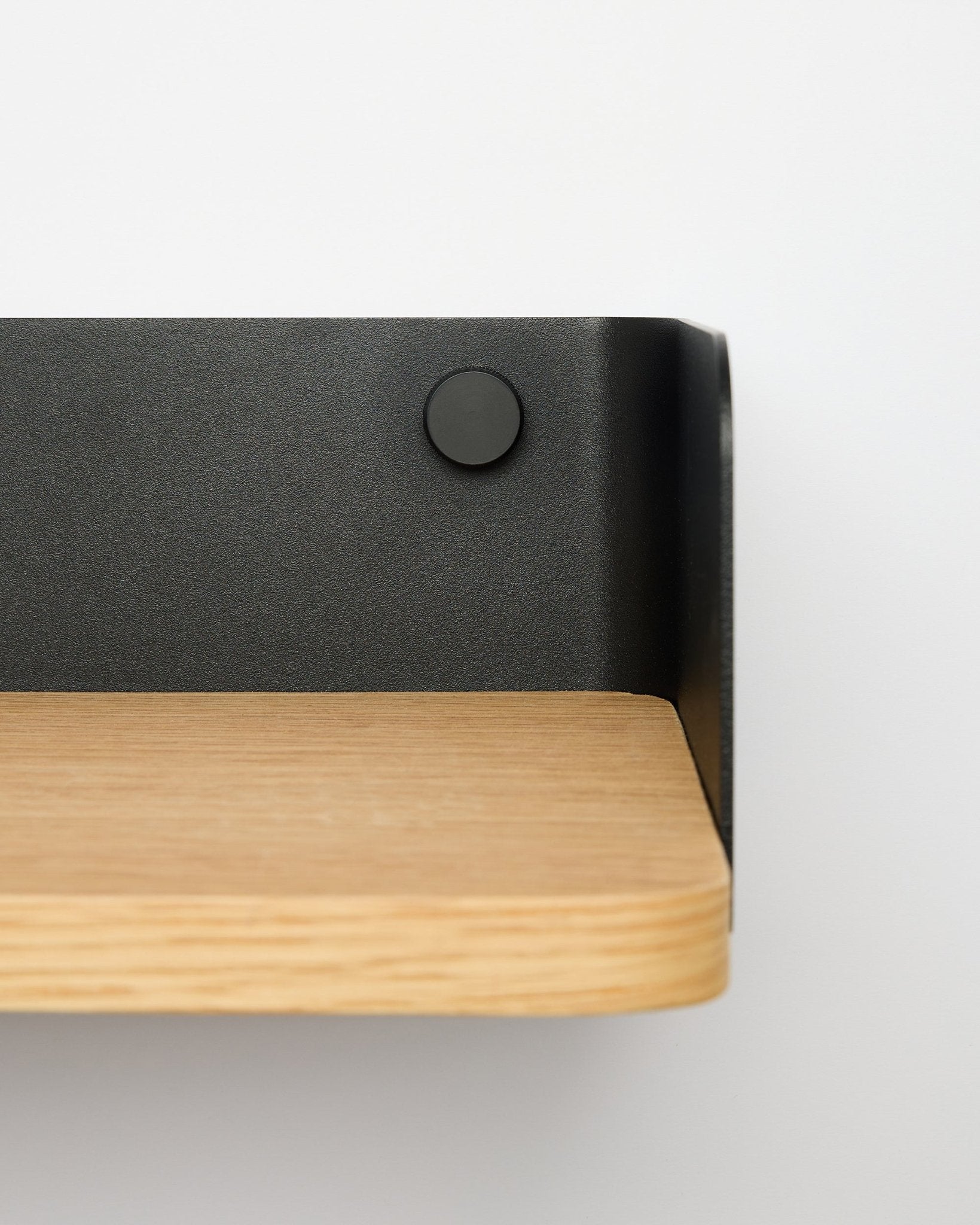 Linn Bookshelf från WoodUpp i natural oak, 55,9 cm bred, med black metallkonsol, monterad på en vit vägg; närbild från höger sida.
