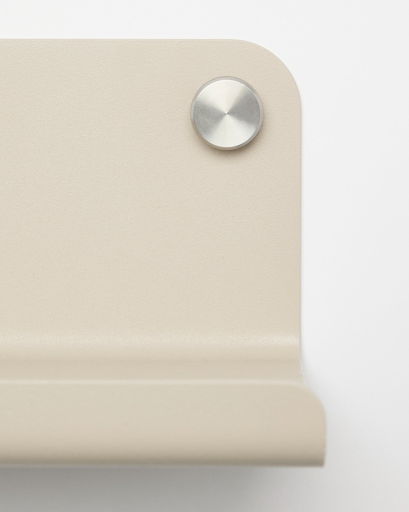 Närbild av ett beige metallhörnfäste med en rund silverfärgad skruv, utformat för WoodUpp Norr breda hylla, 35,9 cm, avbildat mot en vit bakgrund.