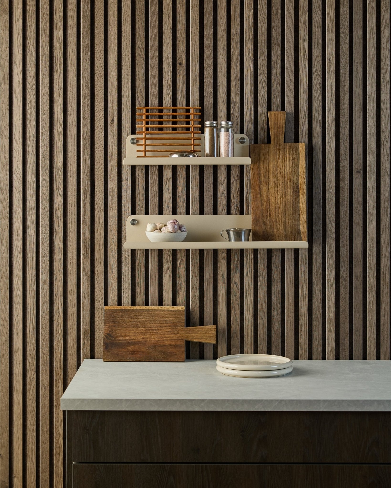 Minimalistiskt kök med nordisk akustikpanel i trä med ribbor i Akupanel, öppna hyllor med kryddor och skålar samt en bänkskiva med vita tallrikar och en skärbräda.
