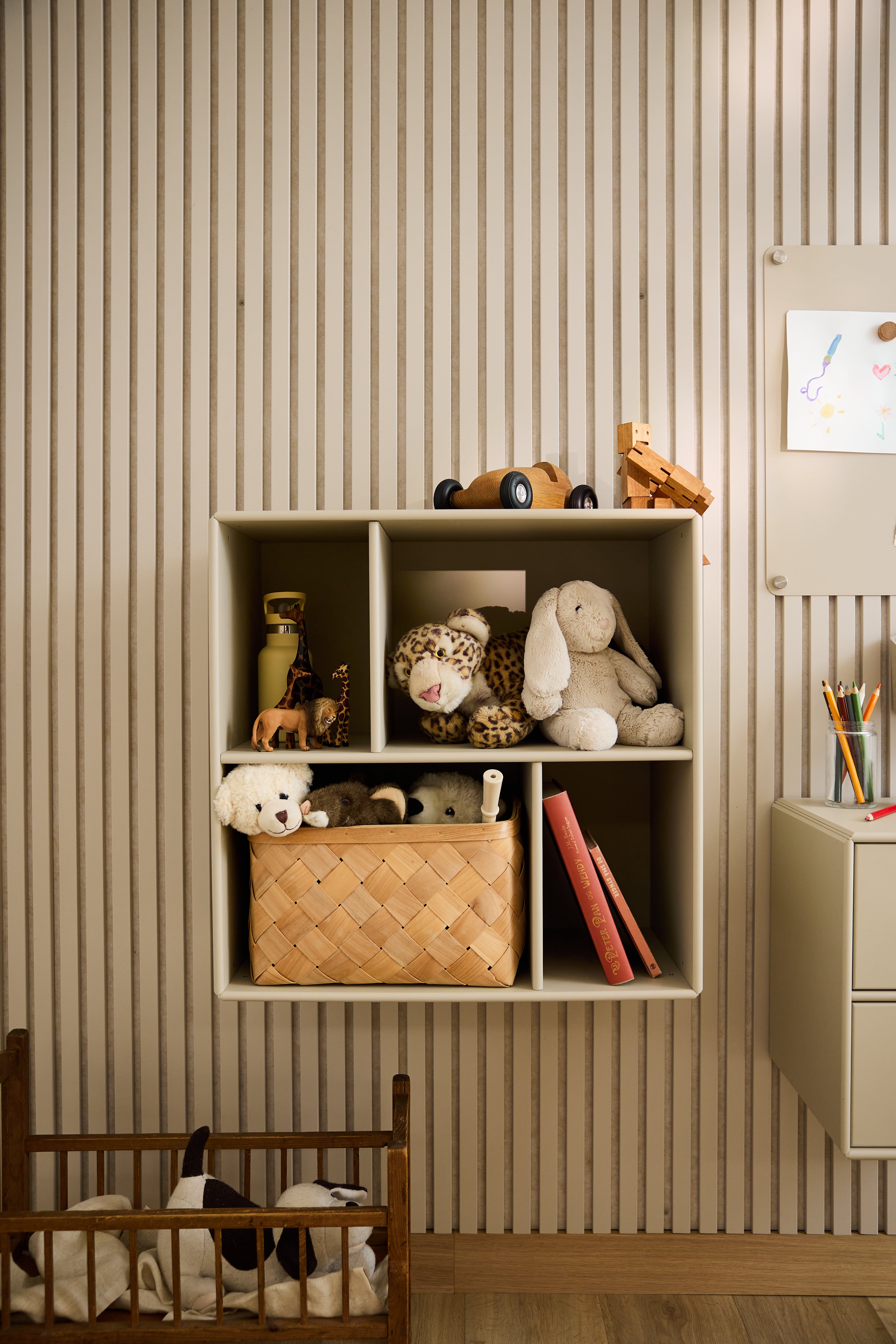 WoodUpp Arka öppet skåp i beige med leksaker och böcker, framför en randig tapet i ett barnrum, visar upp minimalistisk nordisk design.