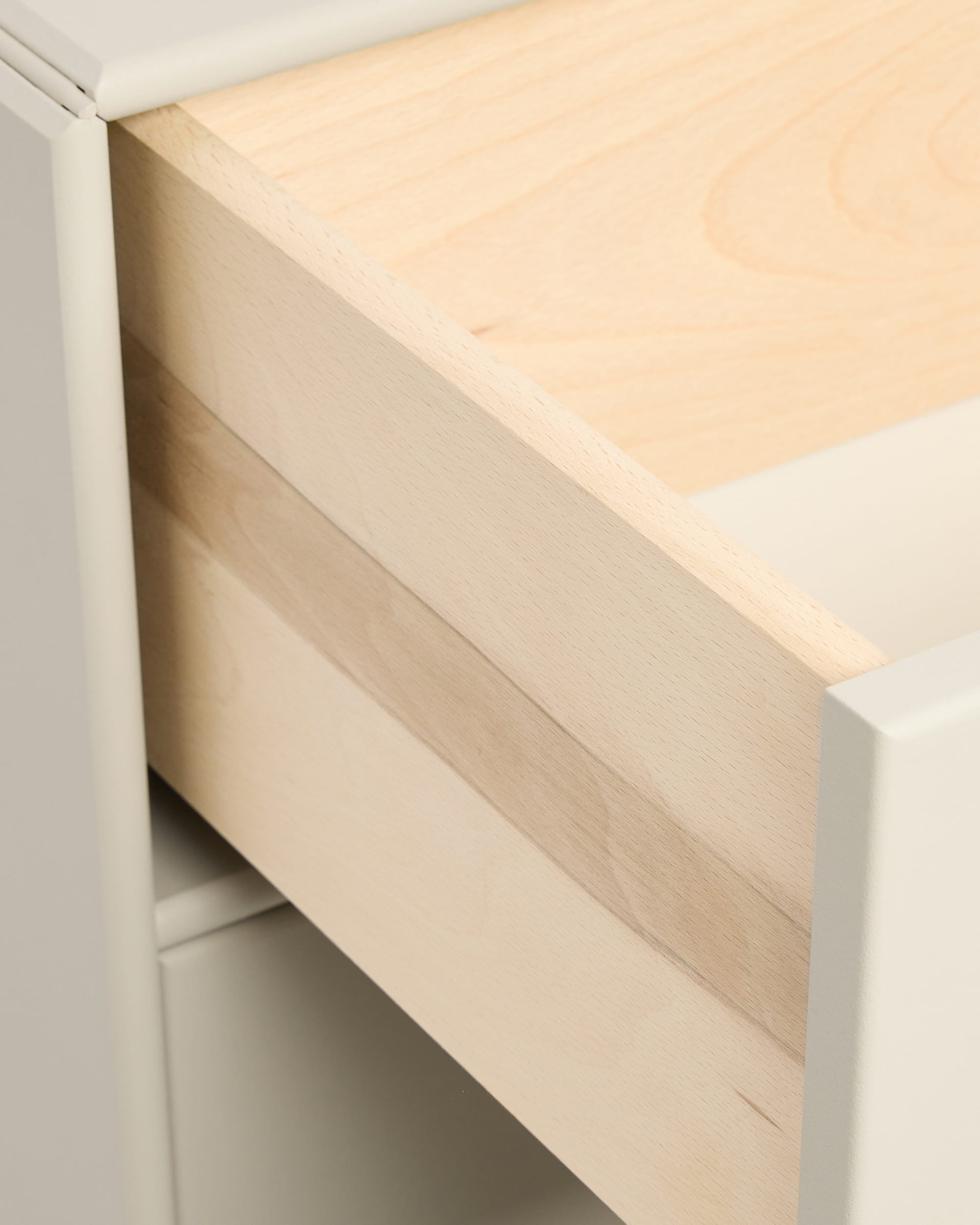 Närbild på en delvis öppen beige Arka-bokhyllelåda från WoodUpp i ett vitt skåp, visad med handtag från CREATE-kollektionen.