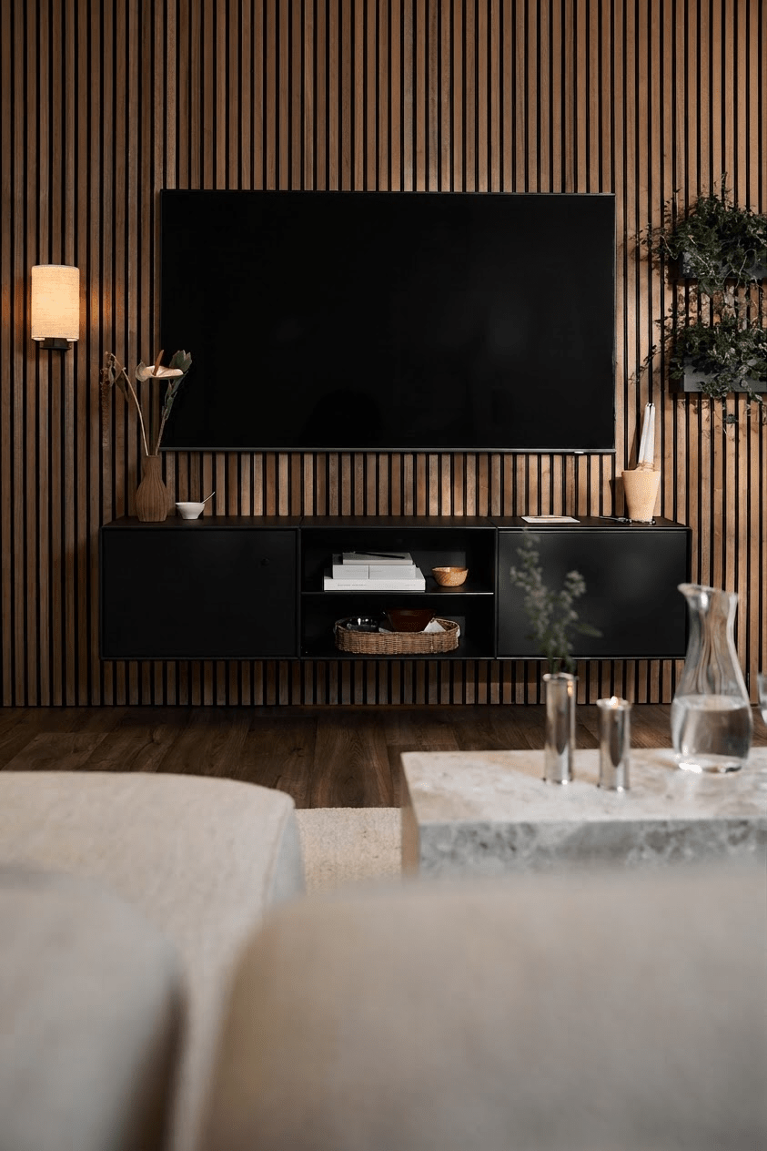 Ett modernt vardagsrum med TV-bänken WoodUpp Arka i svart, en vägg med Akupanel-lameller, minimalistiska inslag och en ljus soffa med soffbord.