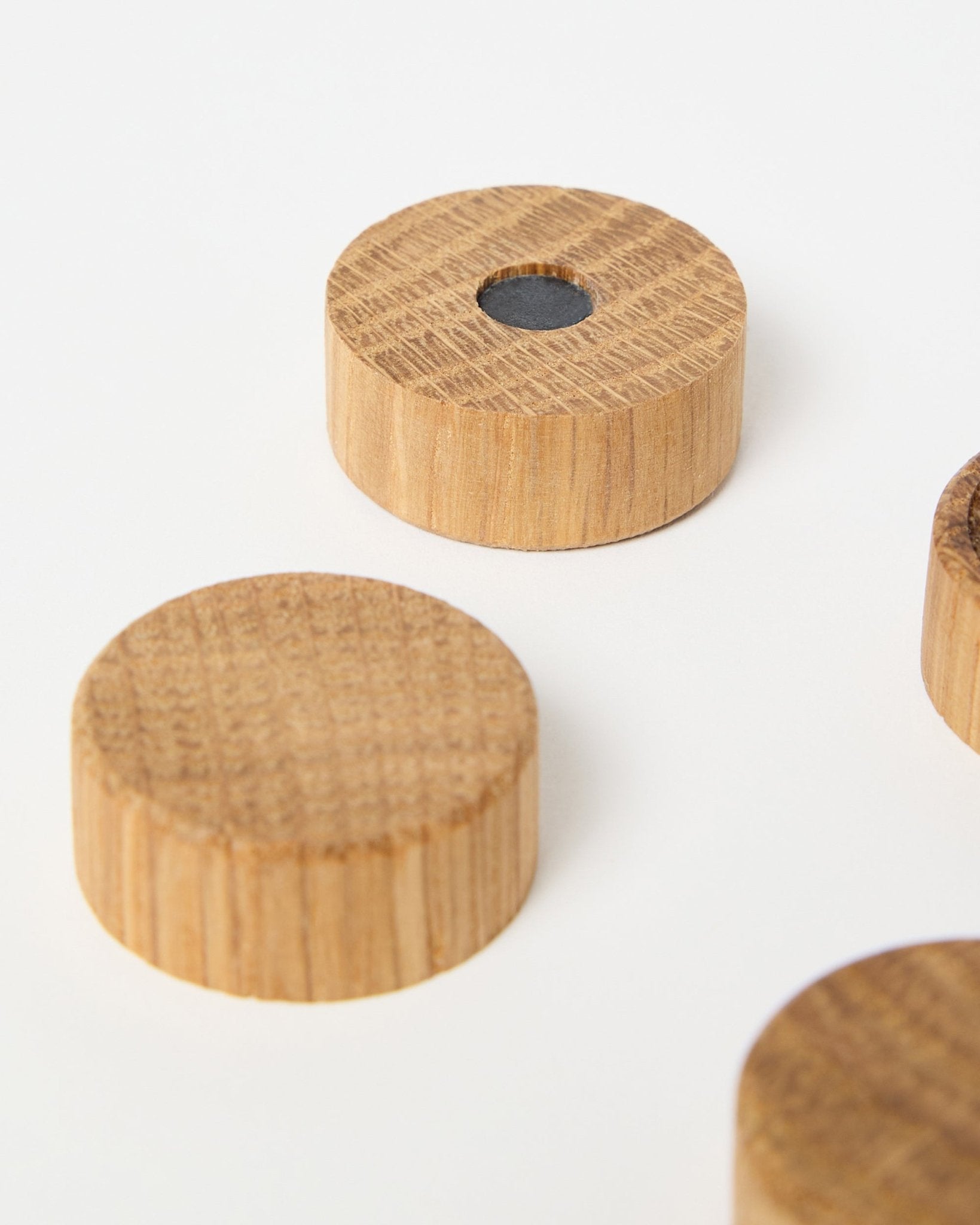 Set med fyra natural oak magneter från WoodUpp, utformade för användning med Akupanel akustiska träpaneler, där en har en central neodymmagnet för extra grepp, visas mot vit bakgrund.