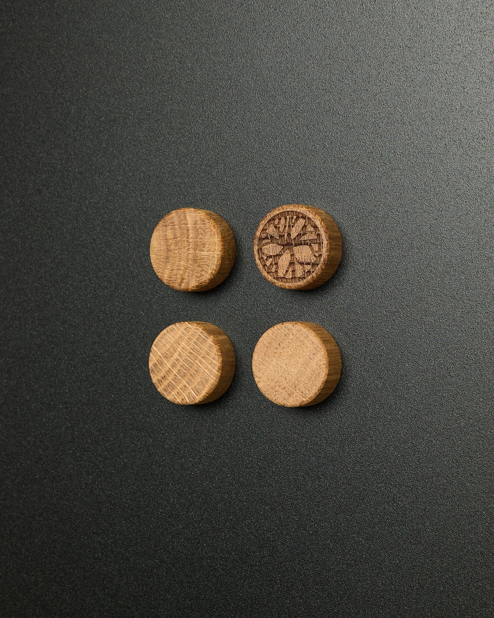Set med fyra magneter i massiv natural oak från WoodUpp, där en har ett utskuret citrusskivemönster, utformat för användning med Norr Magnetic Board Akustikpanel.