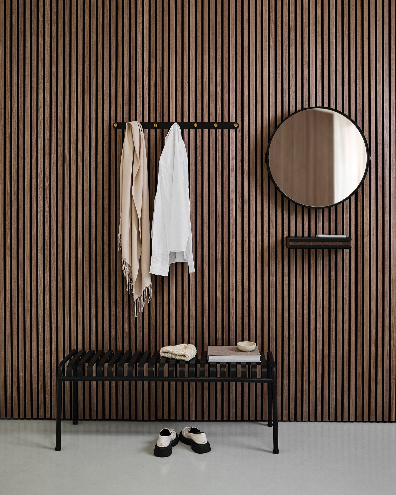 Minimalistisk hall med en WoodUpp Linn | Mirror i Black Oak, nordisk akustikpanel med ribbor, bänk, hylla, hängande kappa och halsduk samt skor på golvet.