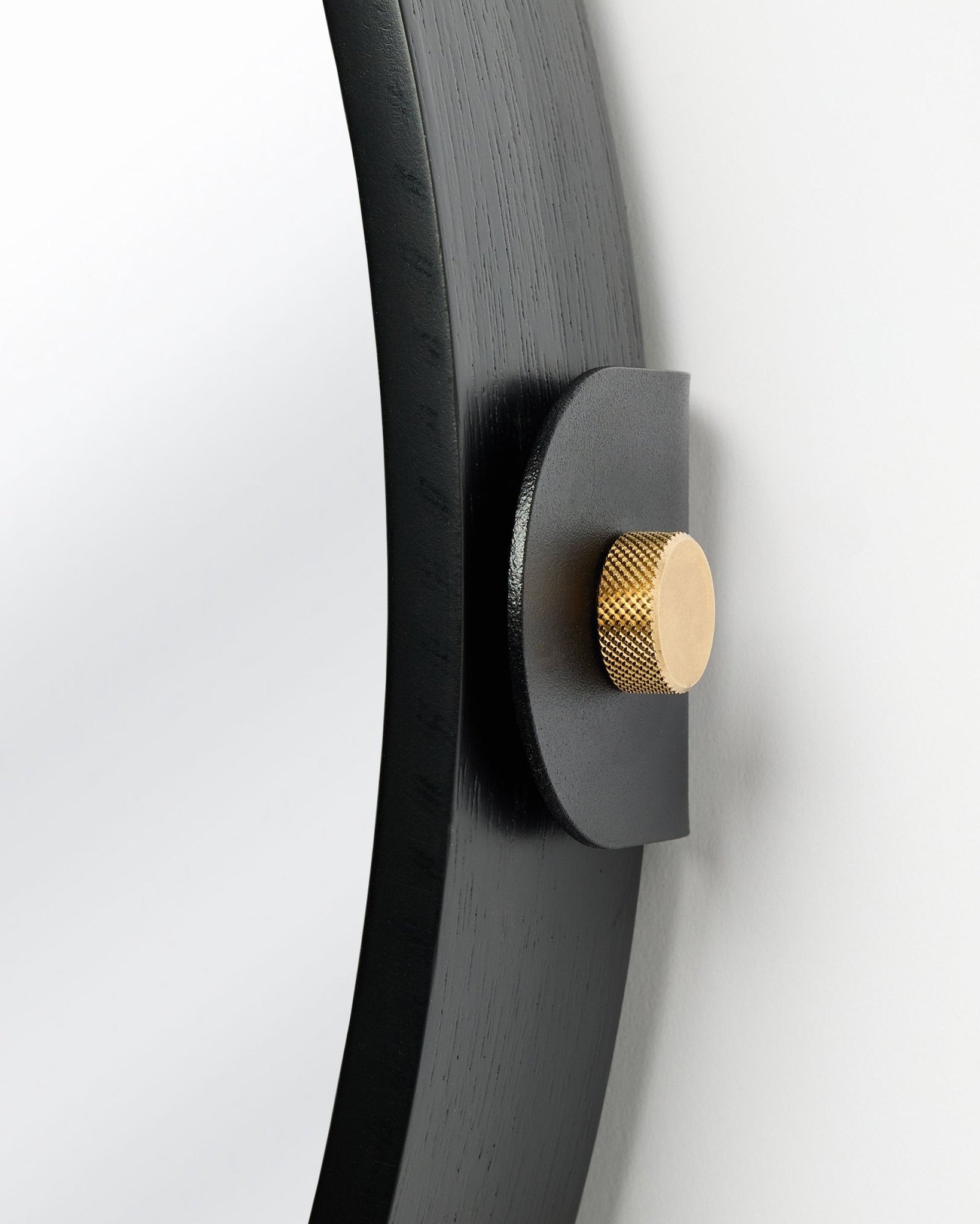 Detalj av Linn | Mirror / Black Oak Akustikpanel från WoodUpp, monterad på väggen med en guldknopp och justerbar lutning.