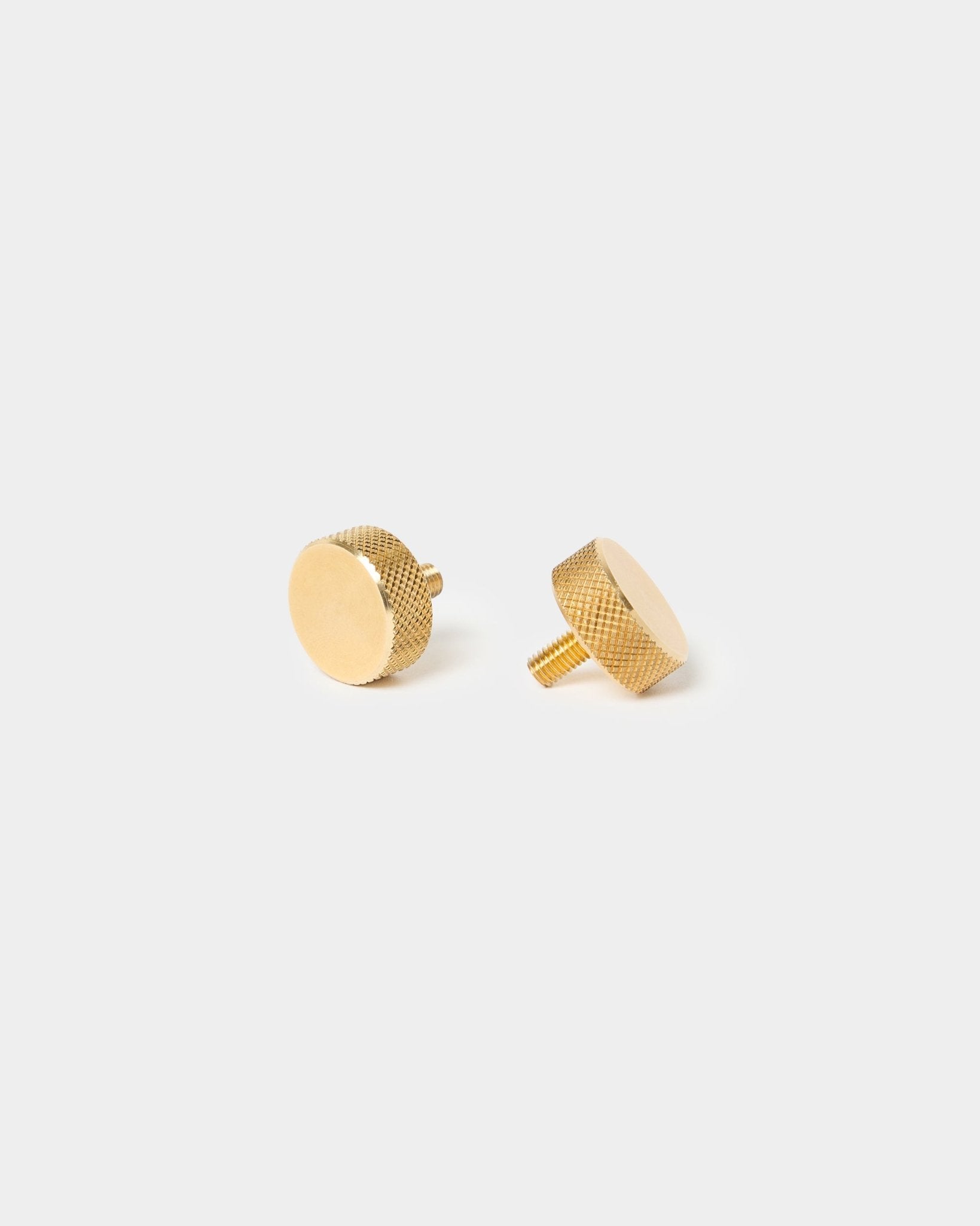 Ett par WoodUpp brass fingerskruvar (M5x10 mm, 20x8.8), med strukturerade kanter och korta skaft, utformade för Akupanel tillbehör, mot en enkel ljus bakgrund.