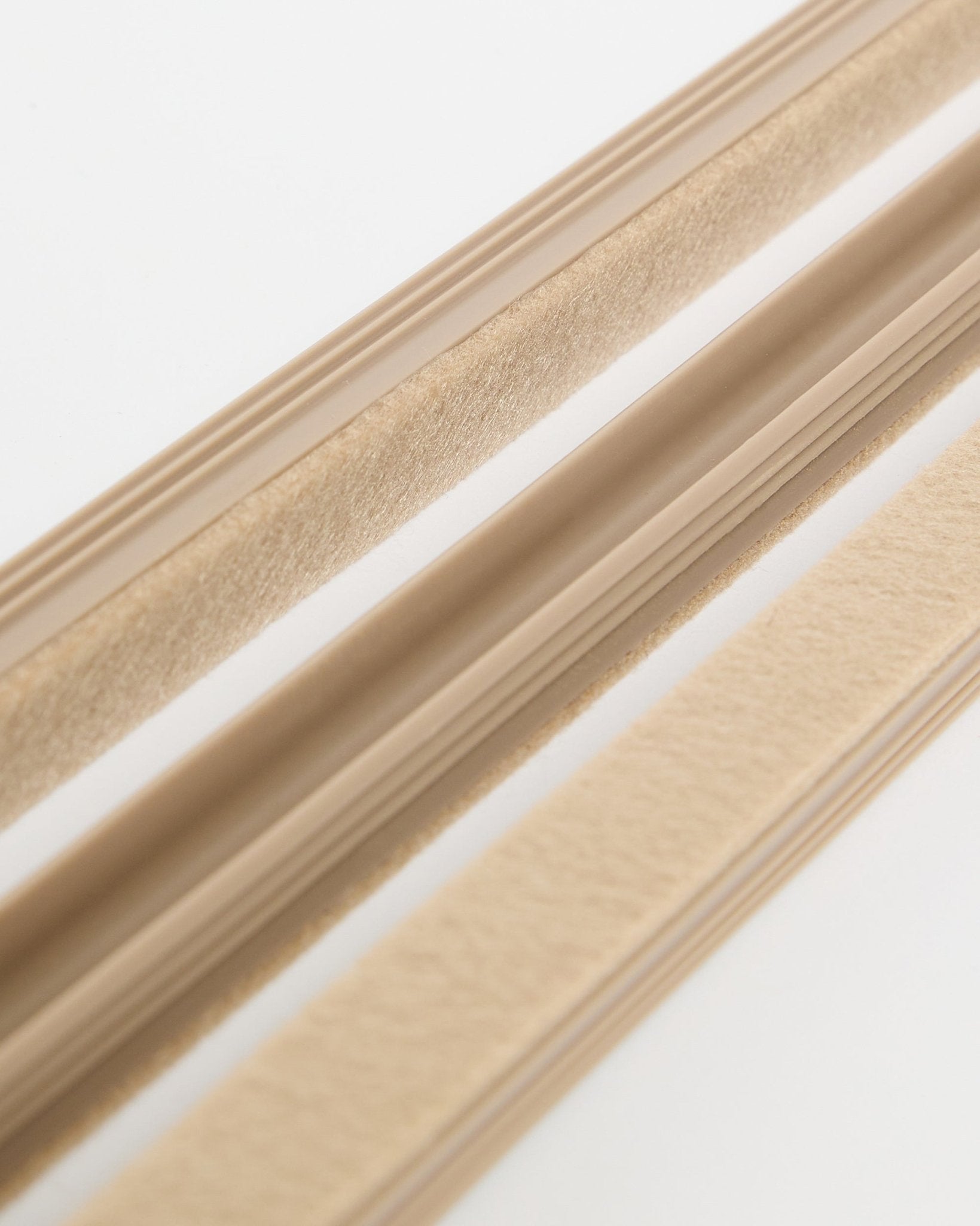 Beige Pop-on Cable Covers från WoodUpp Dupps (3-pack) med filtstruktur och självhäftande baksida, visade på en vit yta för att organisera sladdar.