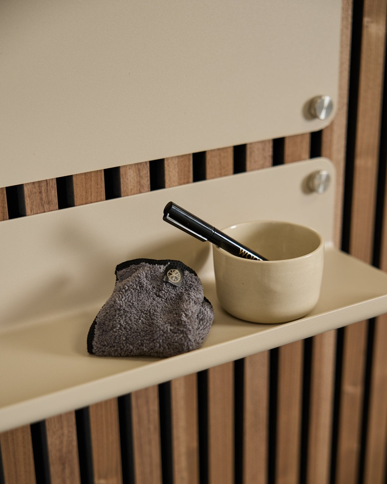 WoodUpps Norr Blackboard-set innehåller en small beige kopp, borste med black handtag och rengöringsduk på en beige hylla med nordisk akustisk träpanel.