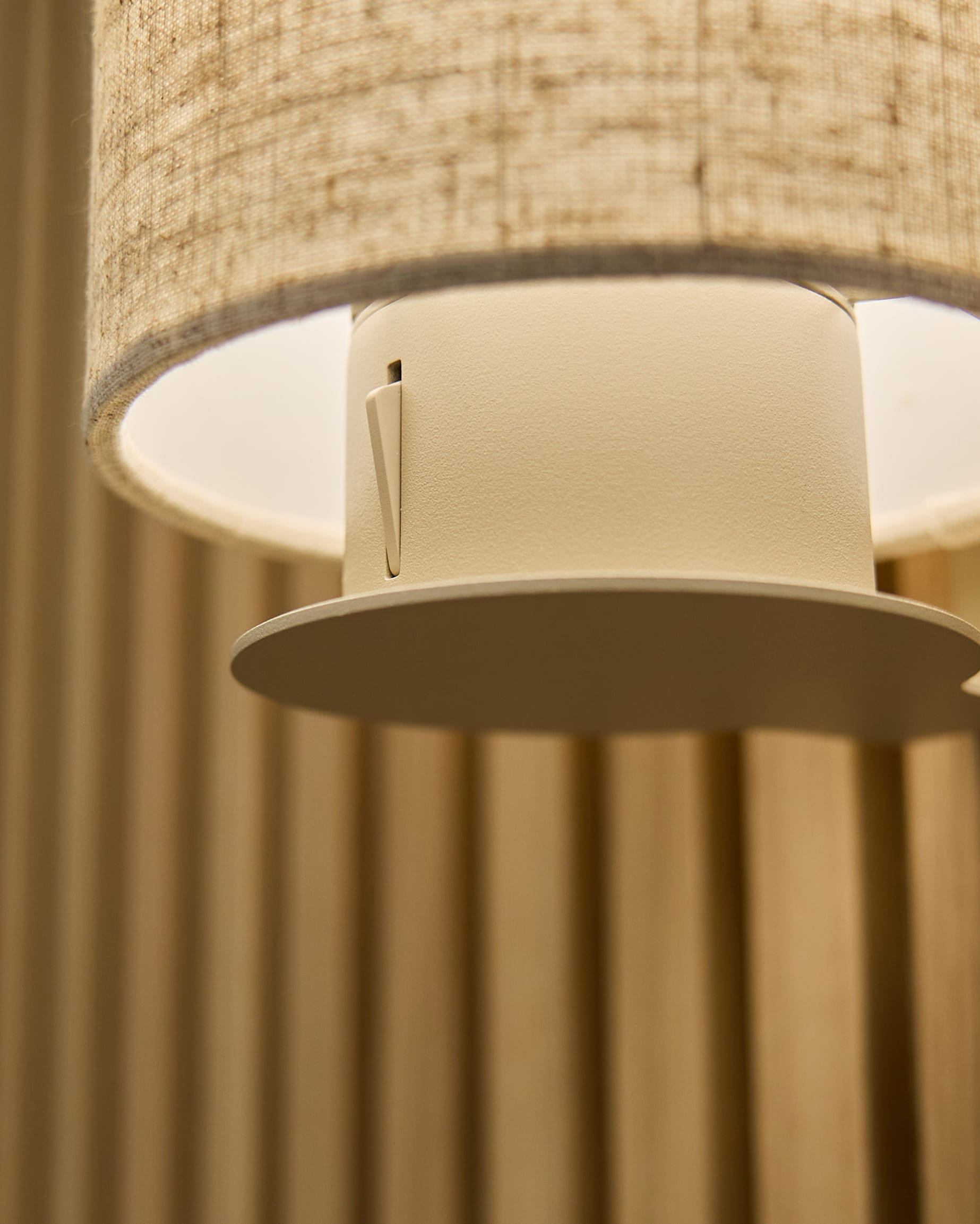 Närbild av Feya vägglampa i Beige/Beige från WoodUpp, med en skärm i linne-bomull och cylindrisk armatur monterad på vertical beige akustikpaneler.