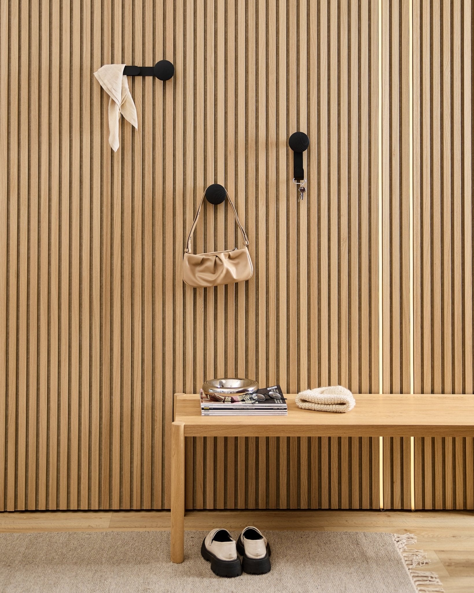 Minimalistisk hall med en WoodUpp Linn Horizontal Hanger i Black Oak med black krokar, träbänk, skor, böcker och ett fat. Nordisk stil.