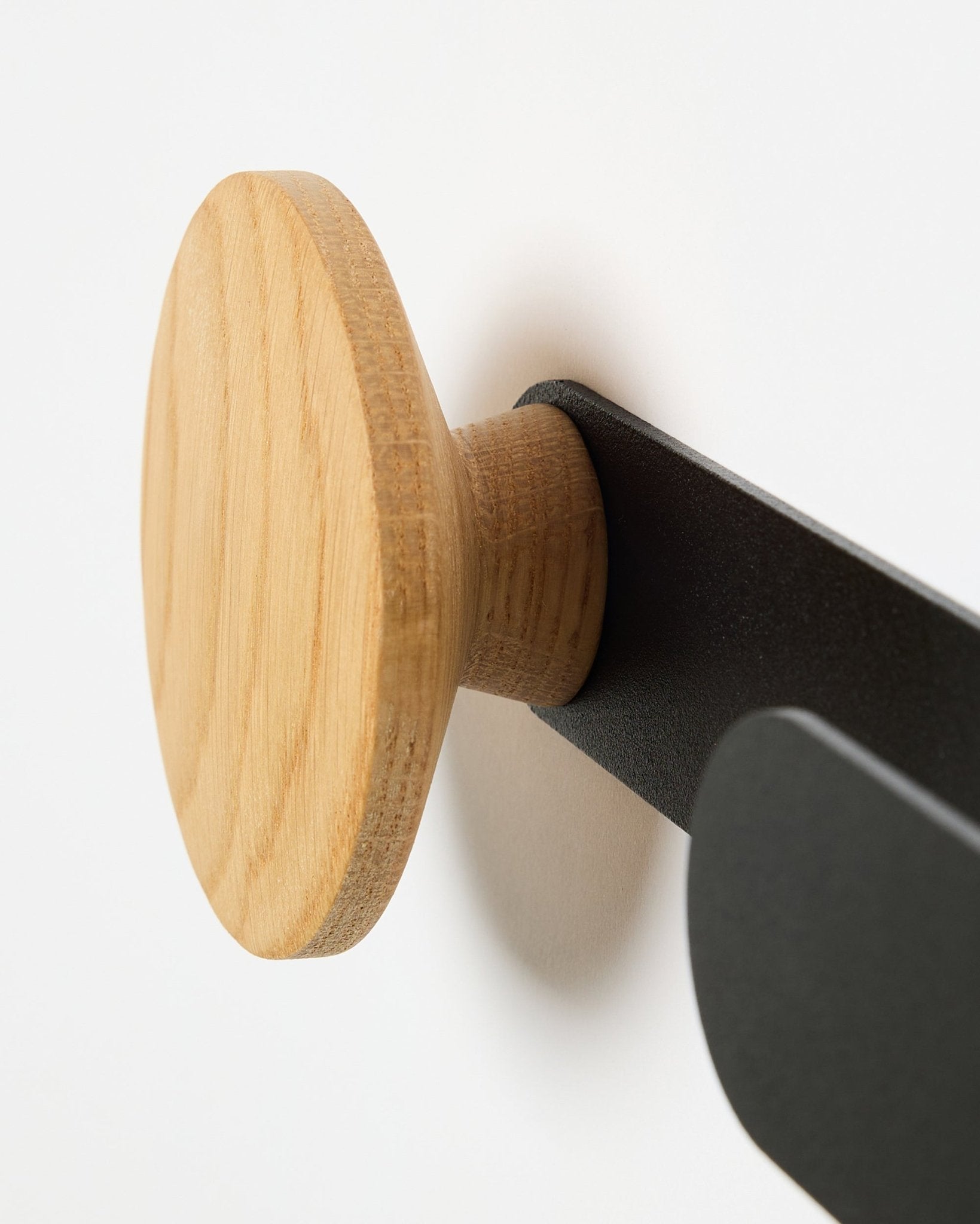 Närbild av WoodUpp Linn Horizontal Hanger i natural oak på en black metallkonsol, utformad för Akupanel akustikpaneler eller som en funktionell väggkrok.