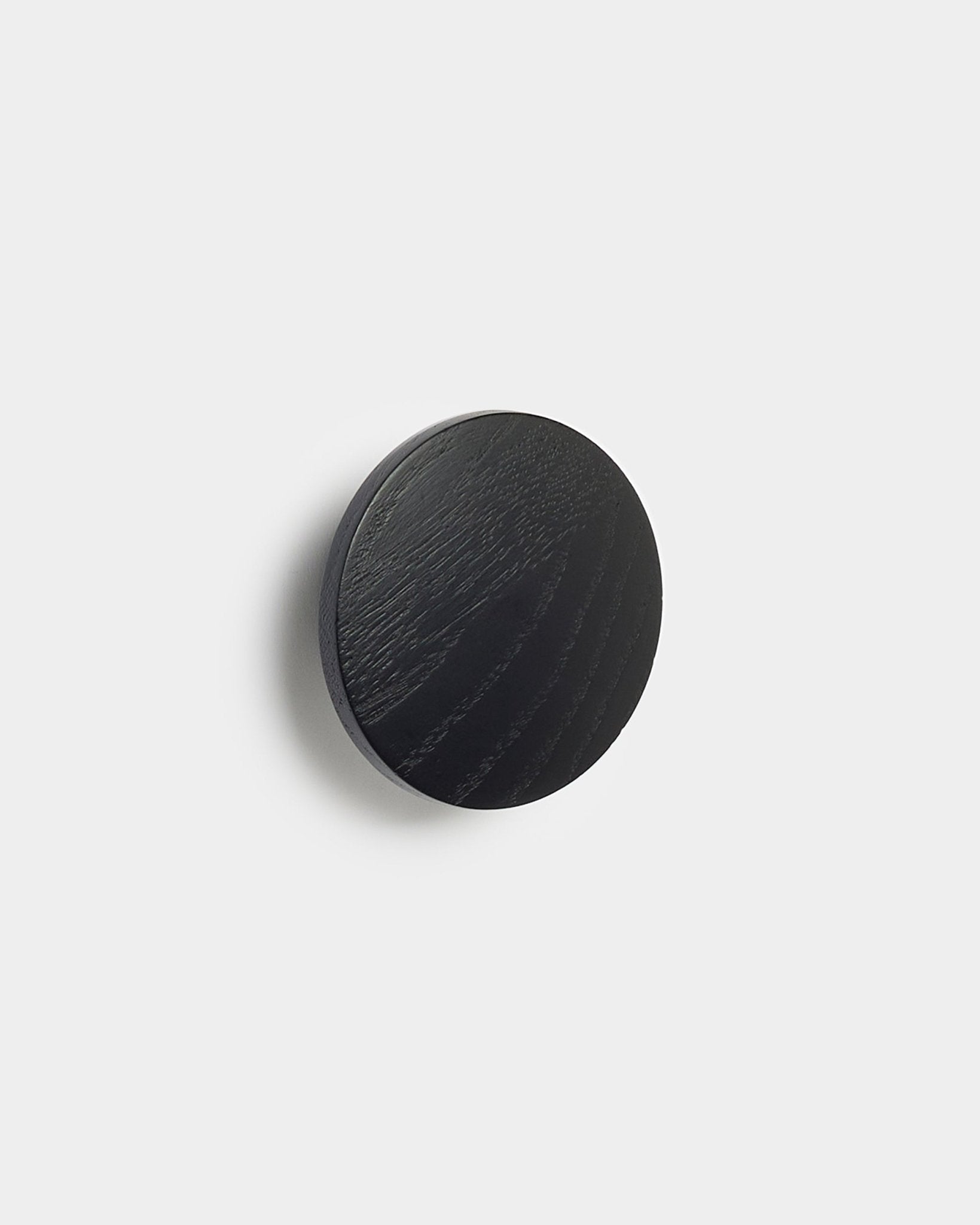 Linn | Single Hanger i black oak från WoodUpp, en rund accessoar för Akupanel akustikpaneler, visad mot en enfärgad vit bakgrund.