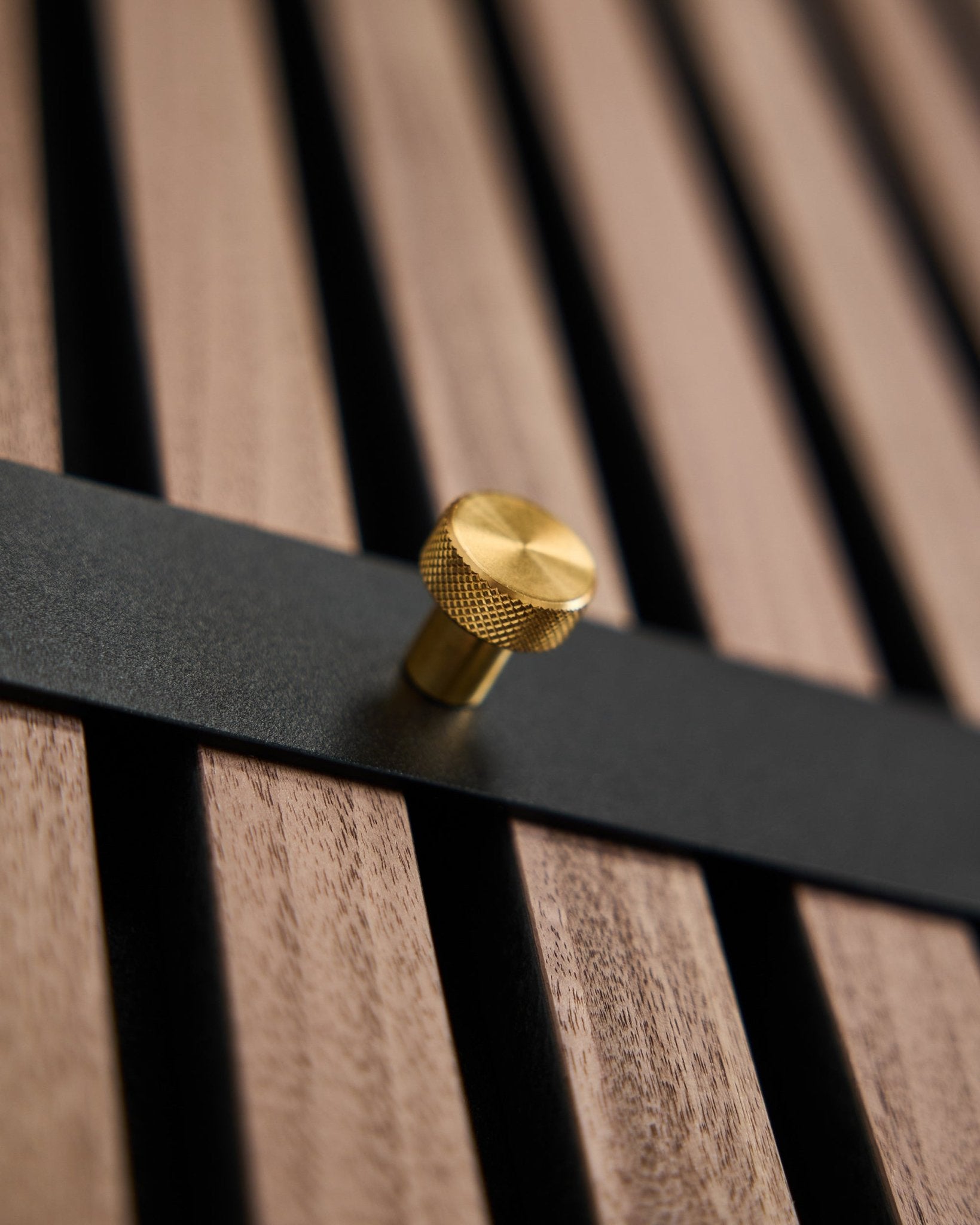 WoodUpp Norr Coat Hook Rack har sju black krokar med brass knoppar monterade på en brown ribbväggspanel, utformad som en nordisk accessoar för Akupanel.