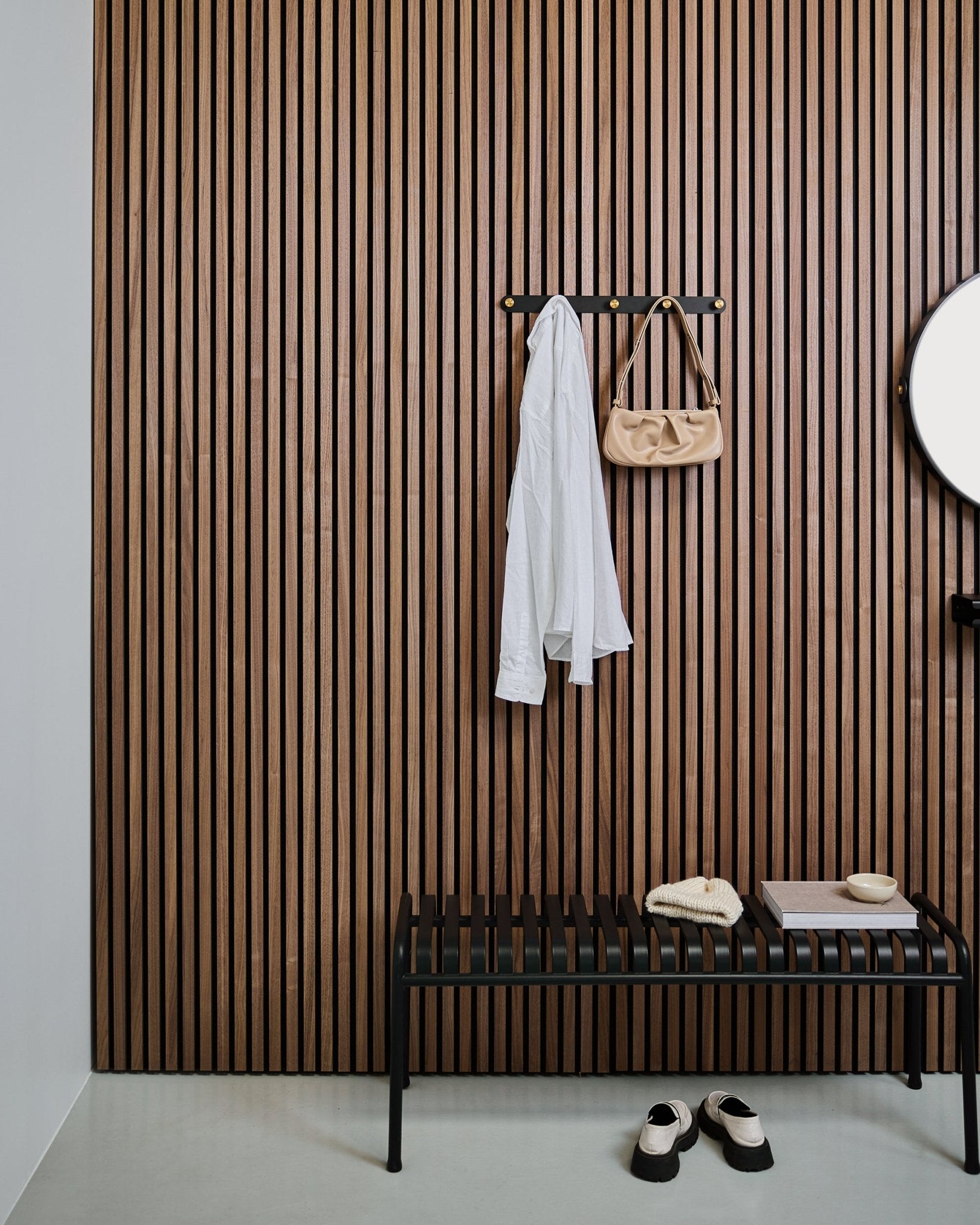 WoodUpp Norr klädkrokslist i black och brass bär upp en vit skjorta och en beige väska ovanför en black bänk; vita tofflor står prydligt placerade undertill.