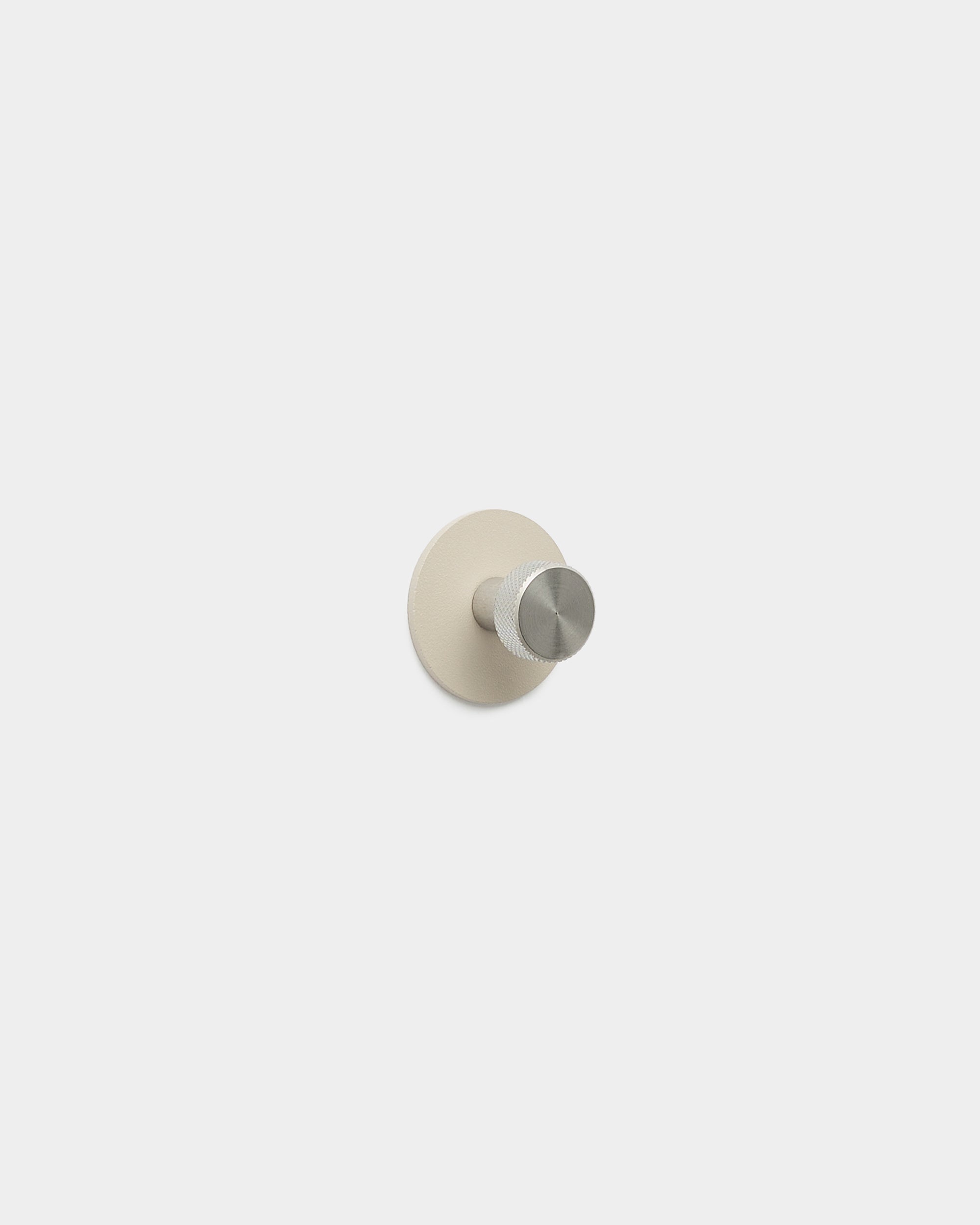 WoodUpp Norr klädkrok i beige och rostfritt steel med minimalistisk krok och rund bas, tillverkad i pulverlackerat steel, en del av WoodUpps tillbehör.