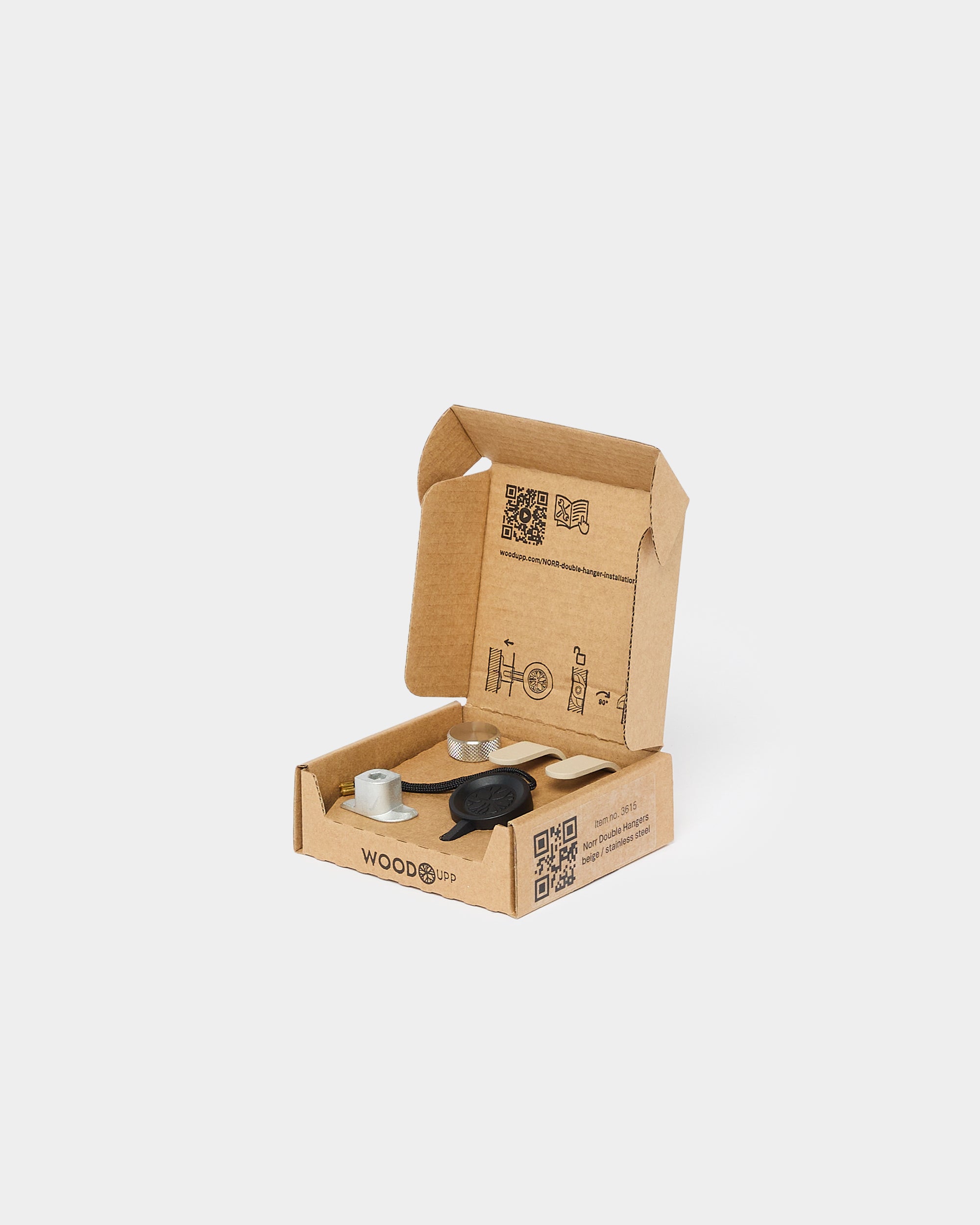 Open brown cardboard box displaying black metal Akupanel mounting hardware, with assembly instructions printed on the inside lid.