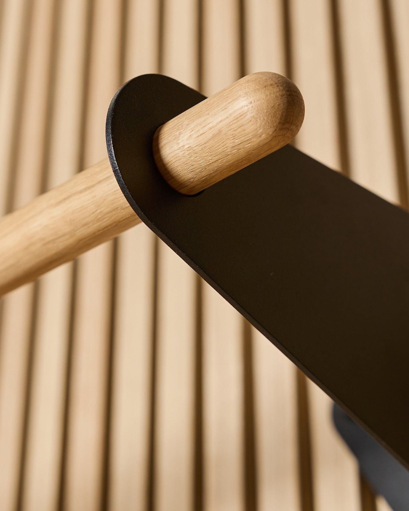 Närbild av WoodUpp Linn Coat Rail i black, 75,9 cm, med en massiv ekstång monterad i ett black metallbeslag på en Nordic akustisk ribbpanel.