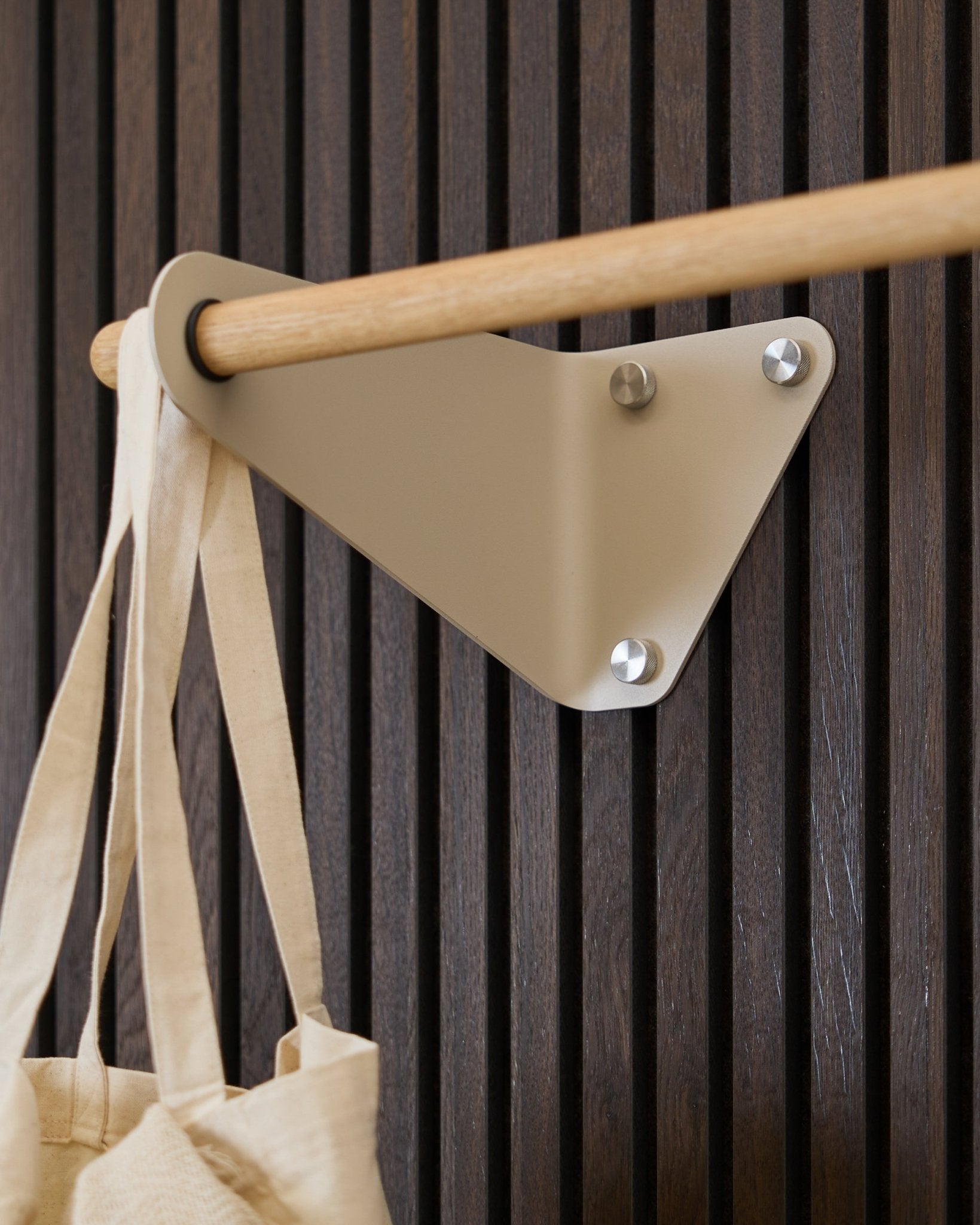 Beige WoodUpp Linn klädhängare (115,9 cm) monterad på Akupanel Akustikpanel, med en cremefärgad tygväska hängande på vänster sida.