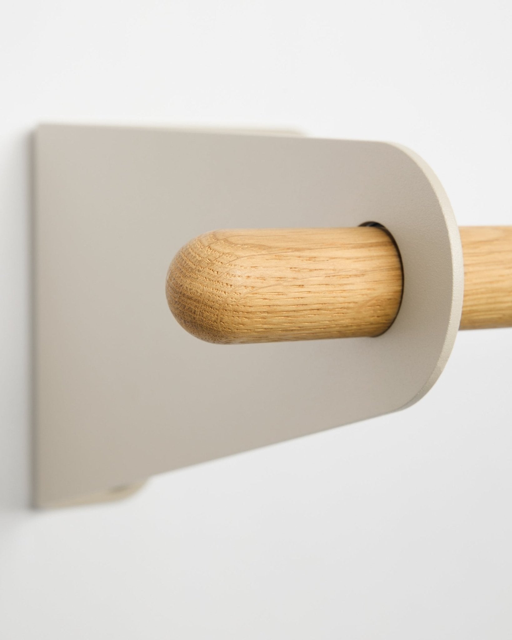 Närbild av WoodUpp Linn klädhängare i beige, 115,9 cm, med ett ljust metallfäste i beige monterat på en vit vägg. Nordisk minimalistisk designaccessoar.