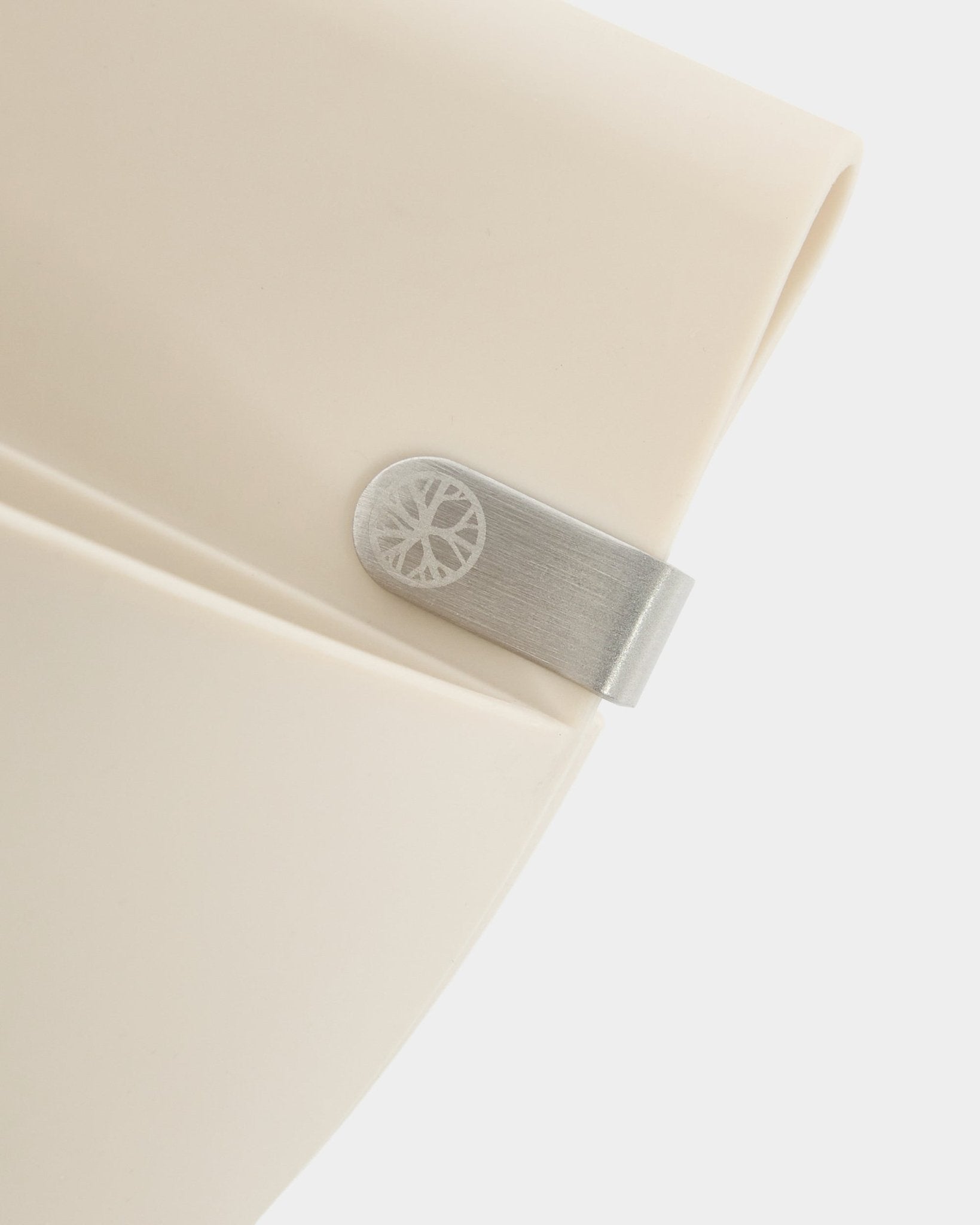 Närbild av en ljus beige WoodUpp Gro | Soft Pocket / BM2-panel (4 l) med metallklämma och graverad cirkeldetalj mot en enkel vit bakgrund.