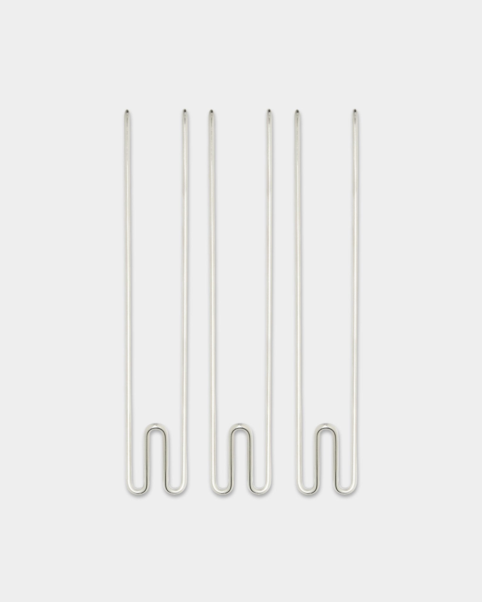 Tre Alva Wire Hook / BM1 tillbehör från WoodUpp, långa krokar i rostfritt steel arrangerade vertikalt mot en enkel vit bakgrund.
