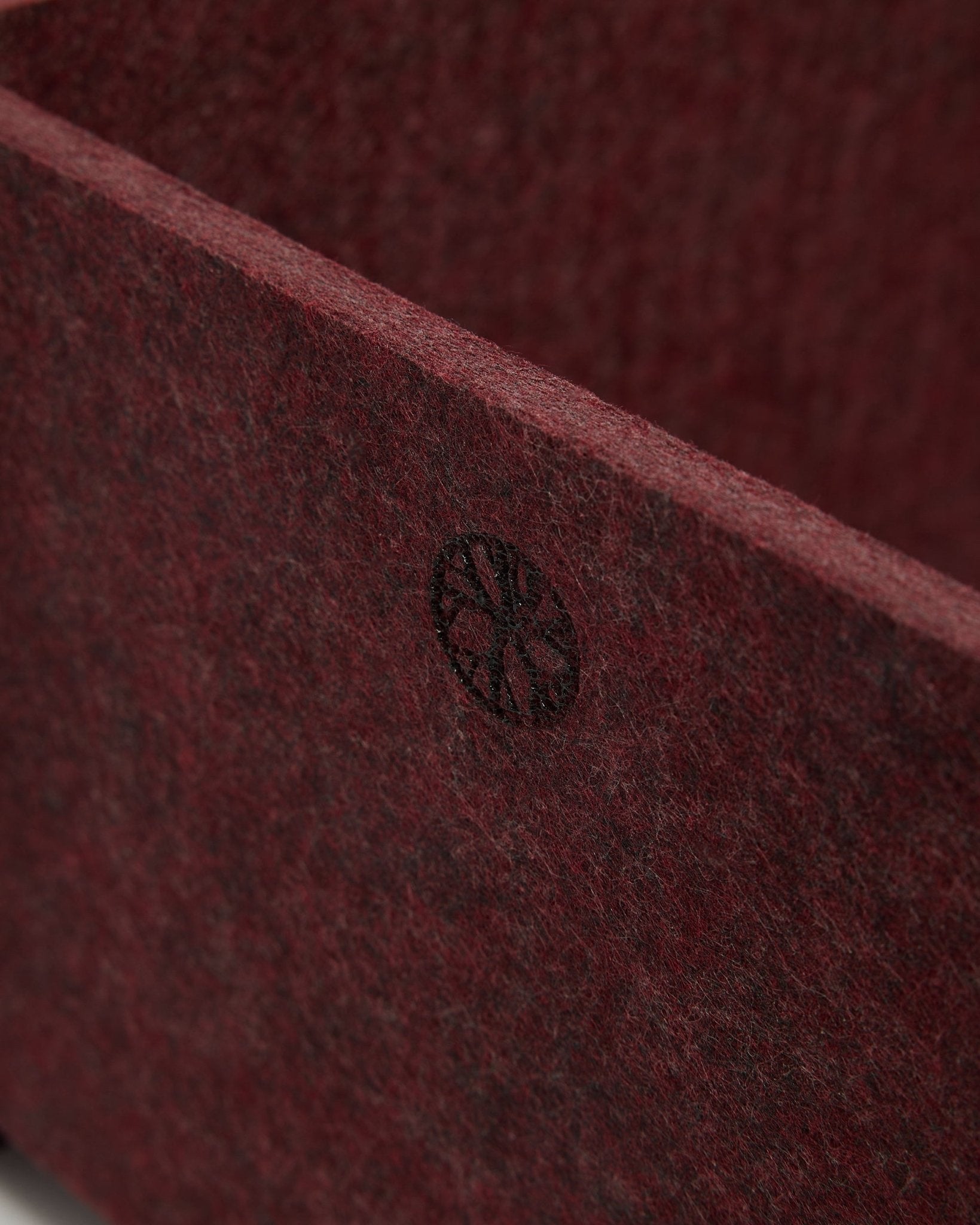 Närbild av WoodUpp Vigg | Felt Box / BM2 i ox red, som visar strukturerad PET-filt och ett cirkelformat black-emblem i hörnet. Nordisk design för akustiska tillbehör.