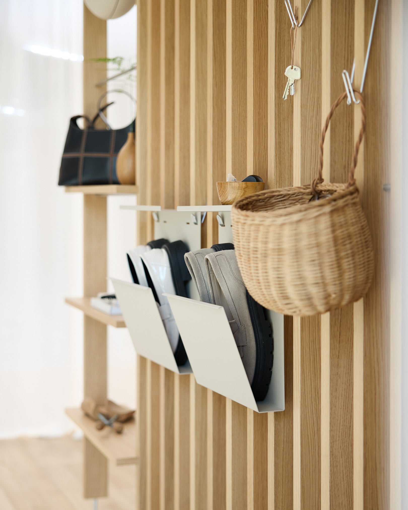 Modern hall med WoodUpps beige Nell skoförvaring, Akupanel akustiska träpanelväggar, väggkrokar, en hängande korg och en hylla med inredningsdetaljer.