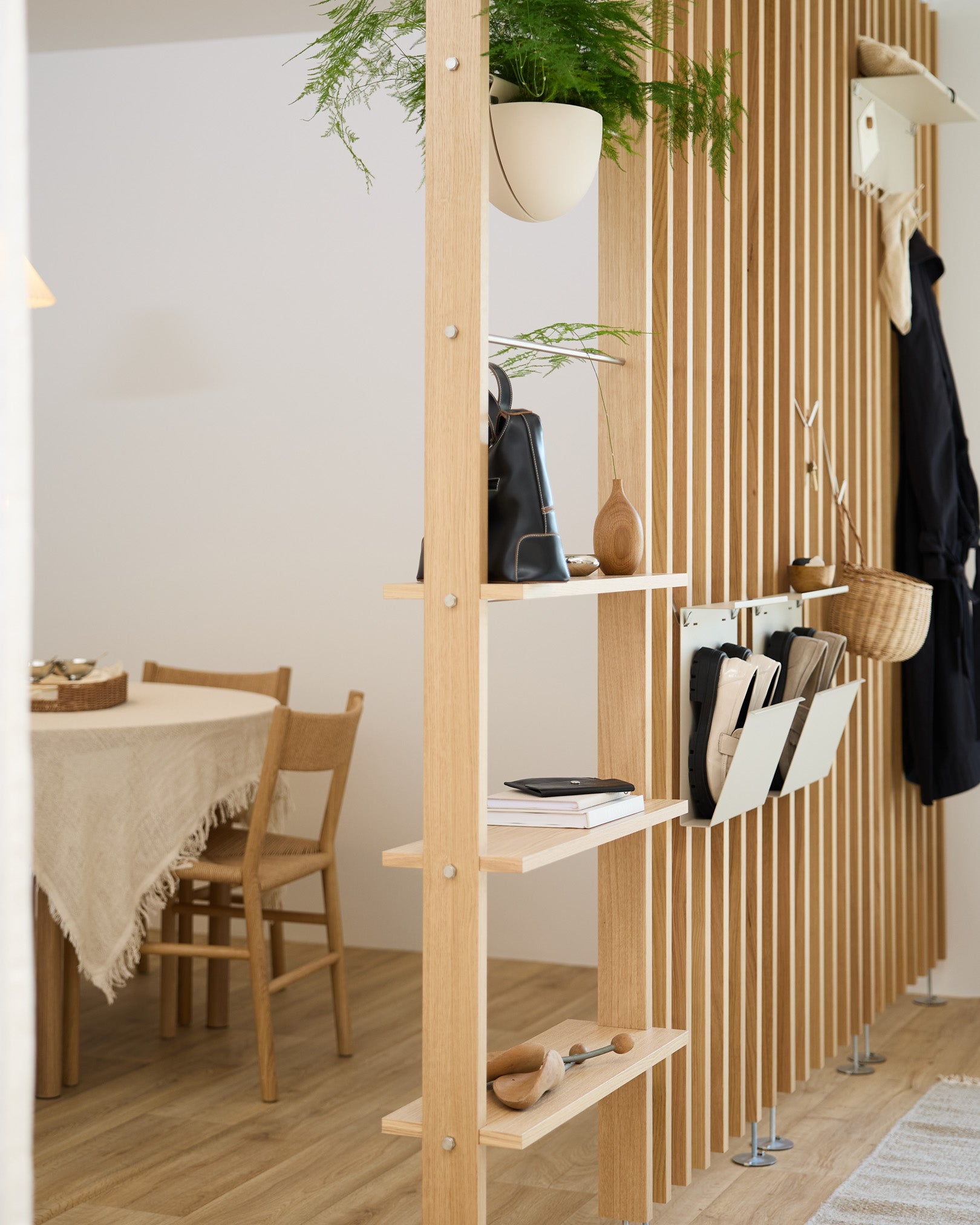 Öppen trähyllning delar av matplatsen och har Nell skoförvaring i beige från WoodUpp för en organiserad plats för skor i ett modernt nordiskt hem.