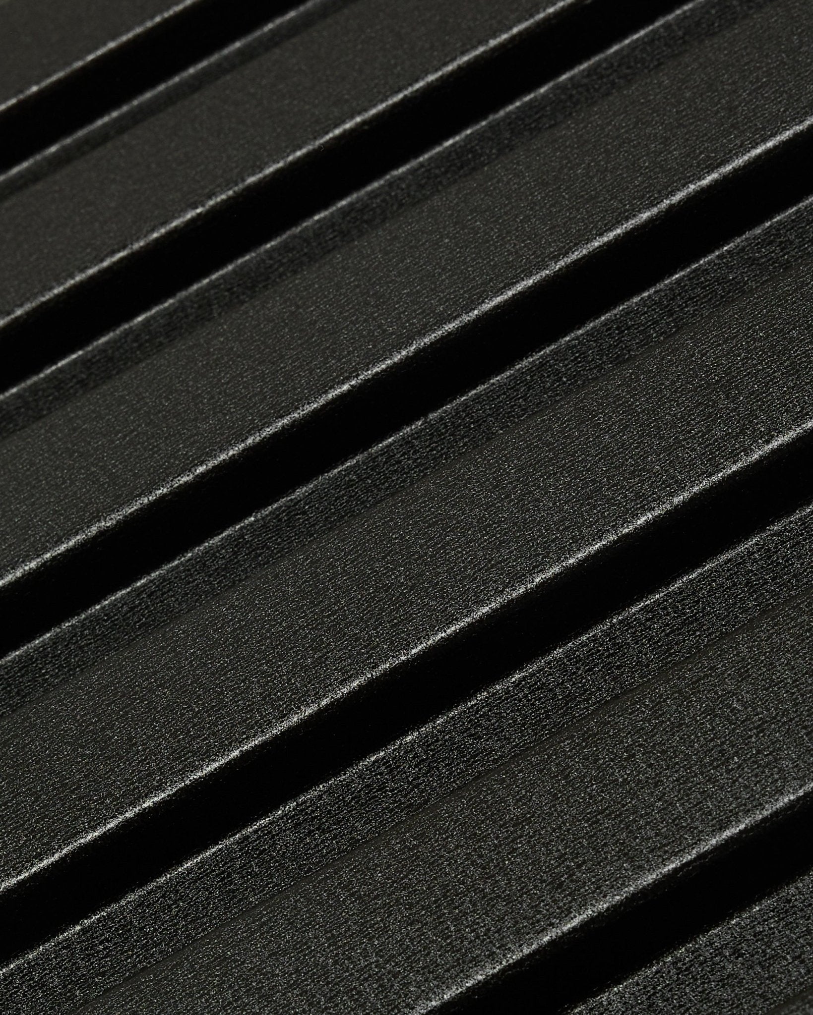 Närbild av Aluwood fasadpanel för utomhusbruk från WoodUpp: mörk, texturerad yta i återvunnen aluminium med diagonala upphöjda räfflor, 240 x 45,1 cm.