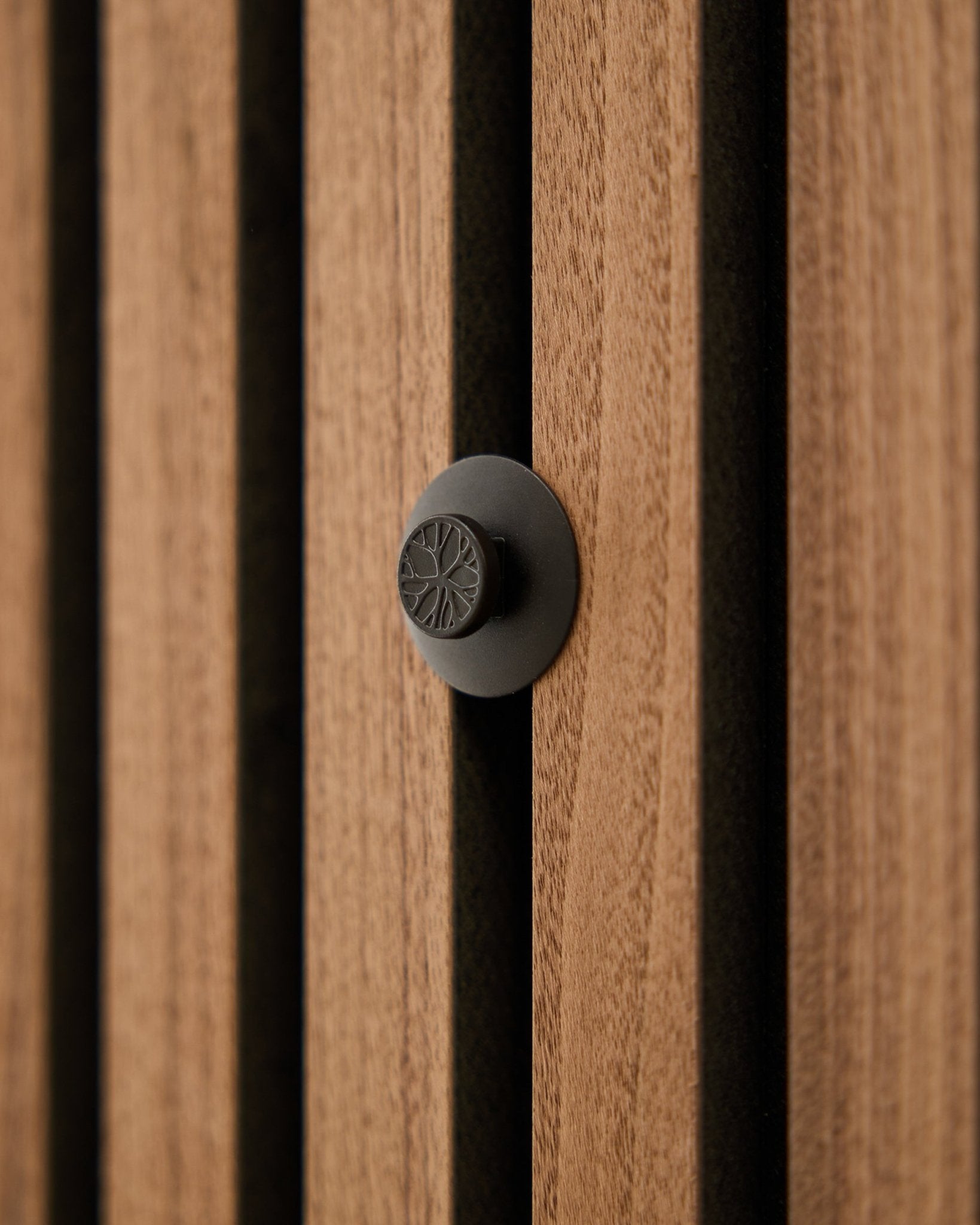 Närbild av en rund black-knopp från WoodUpp Dupps Original-set, monterad på en modern vertical Akupanel akustisk träspaltvägg.
