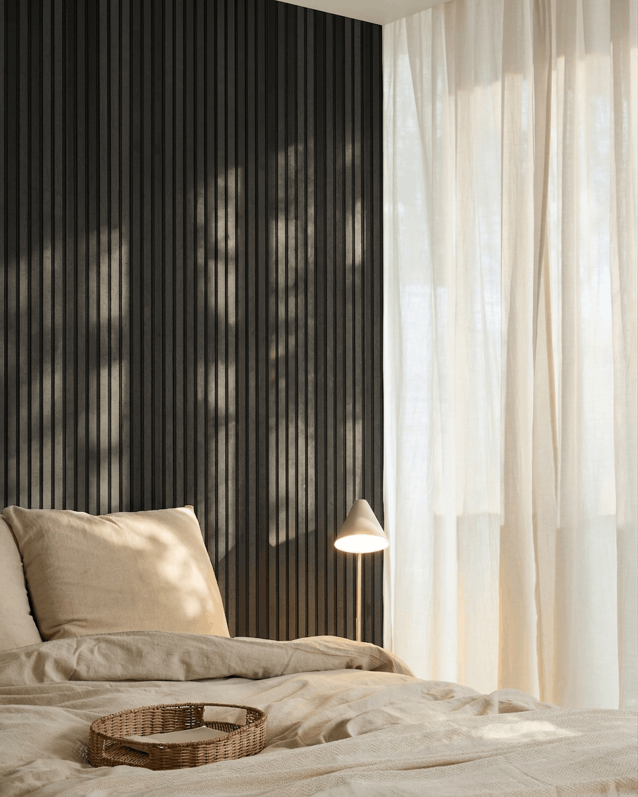 Minimalistiskt nordiskt sovrum med en WoodUpp Akupanel Akustikpanel i Black Ash, beige sängkläder, en bricka i rotting och skira gardiner som släpper in naturligt ljus.