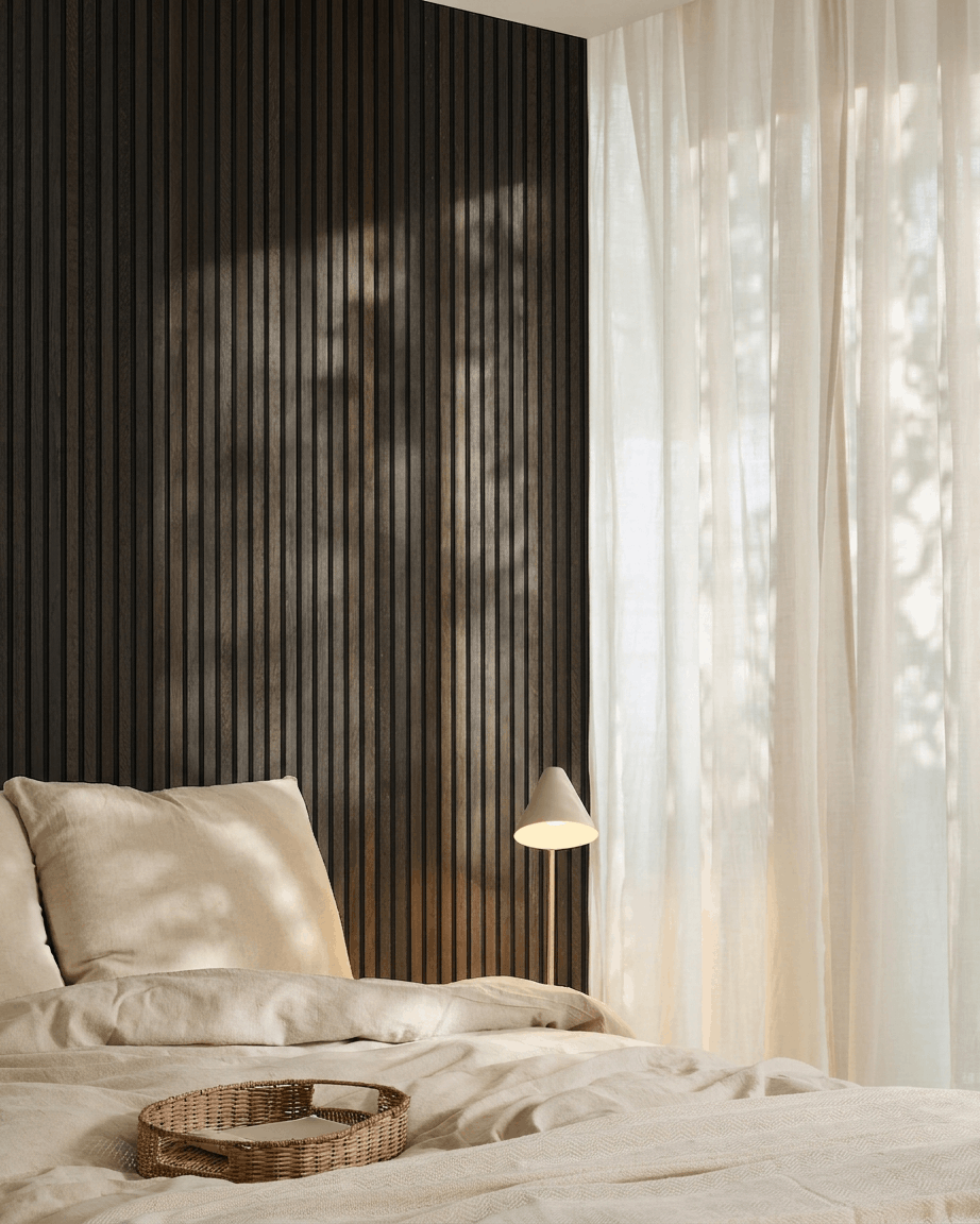 Minimalistiskt sovrum med en beige säng, bricka i rotting, Scandi-detaljer och WoodUpp Akupanel akustikpanel i trä i Rustic Smoked Oak monterad på en mörk vägg.