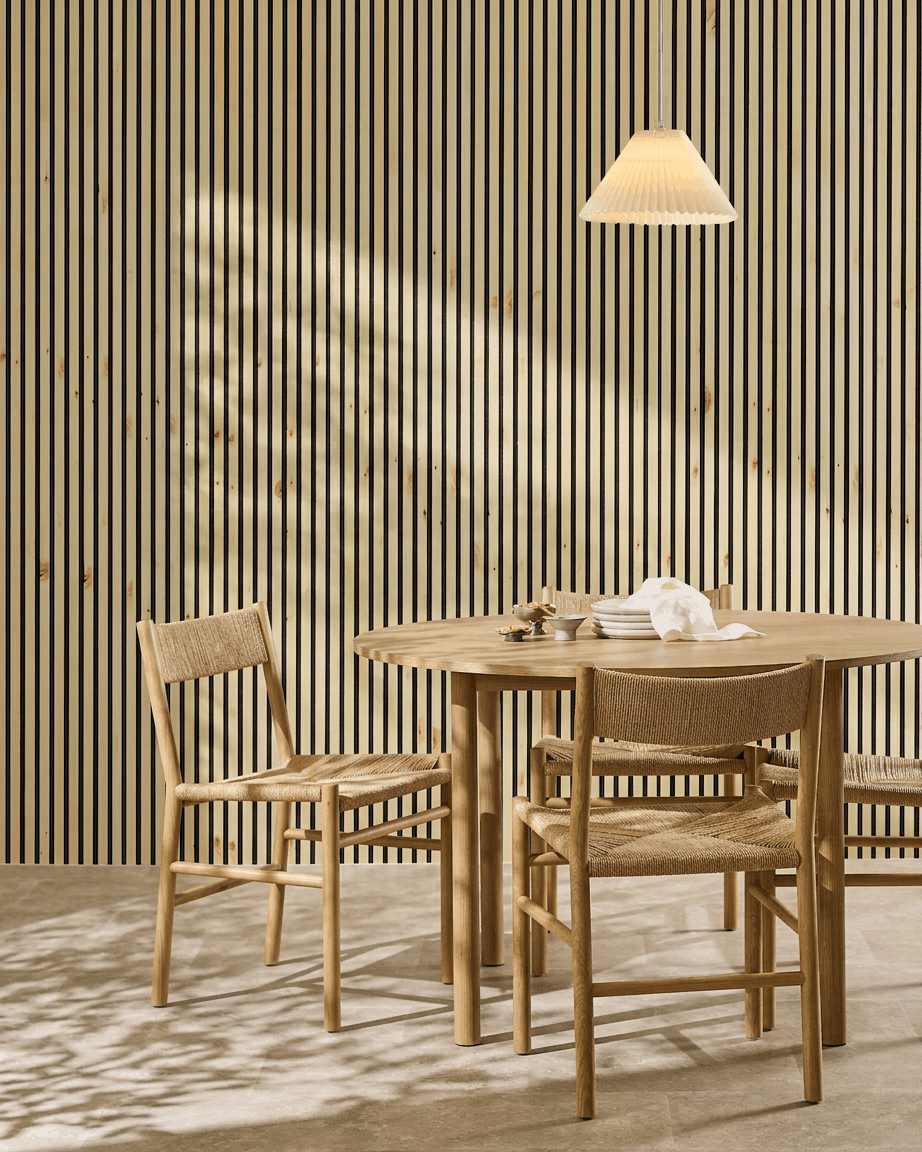Akustikpanelen WoodUpp Akupanel i naturligt trä, al och svart filt ger en varm, minimalistisk nordisk prägel åt en skandinavisk matplats med bord och stolar.